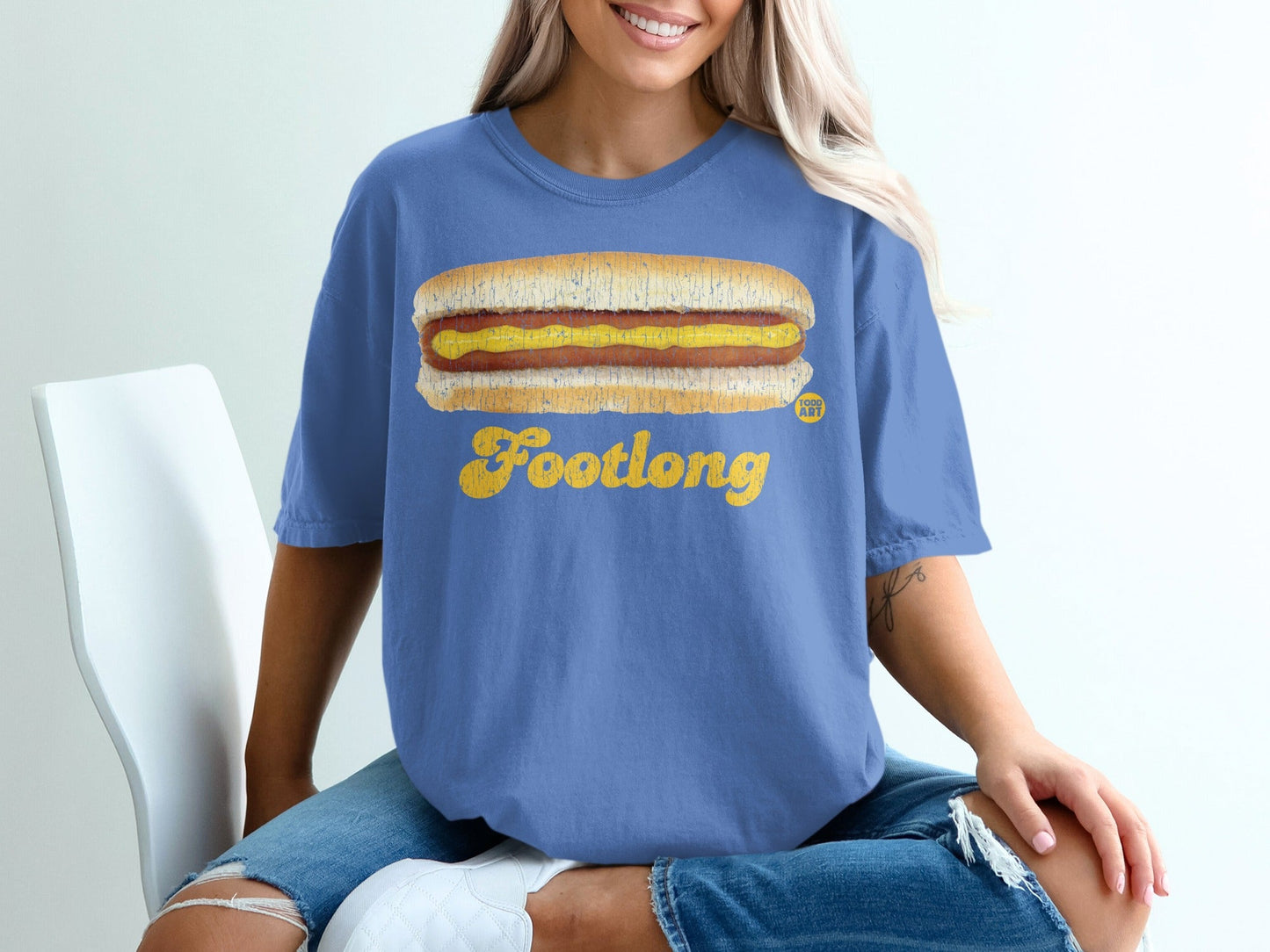 Blue t-shirt with a yellow "Footlong" hot dog graphic and mustard.
