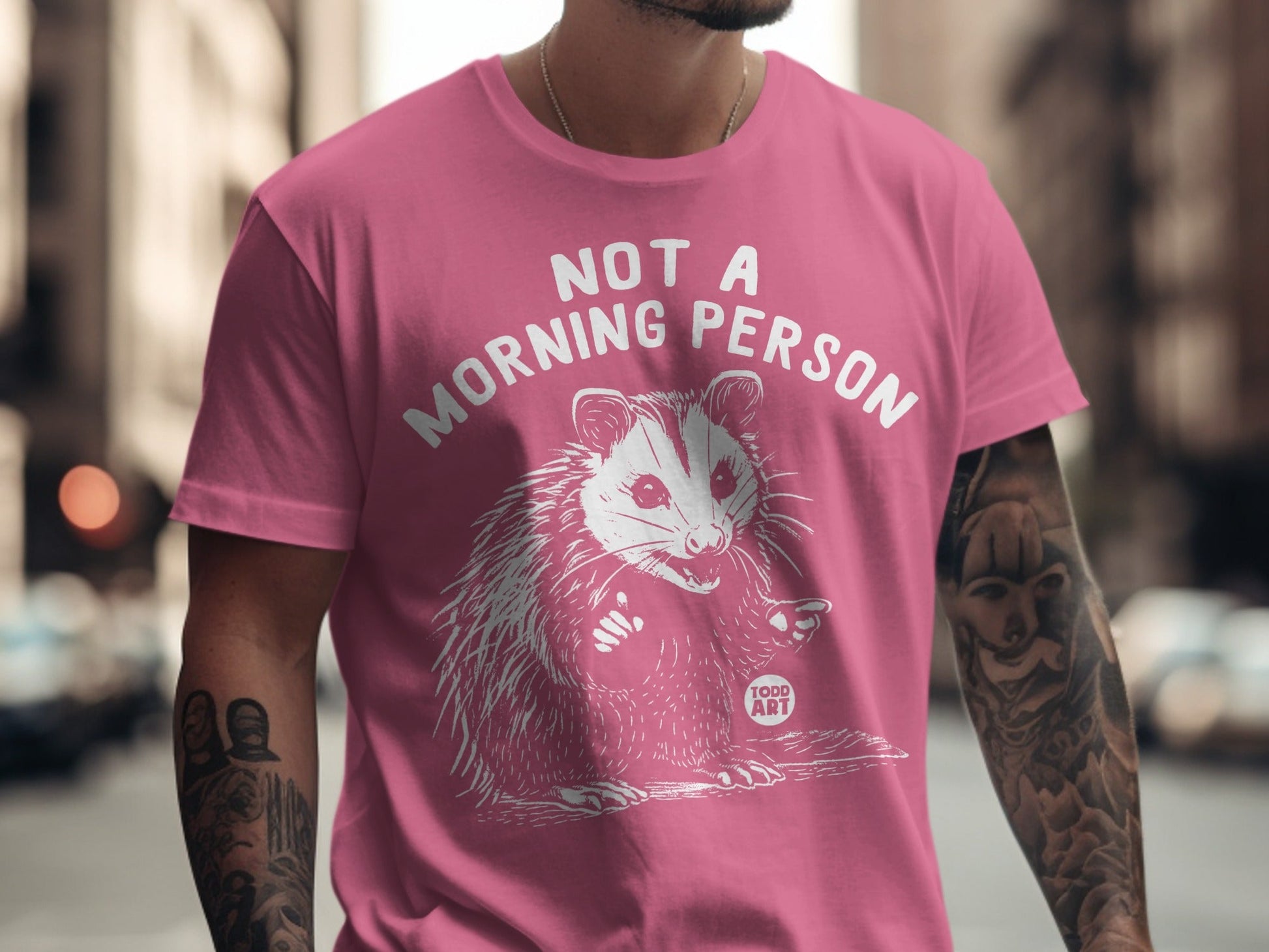 Pink t-shirt with "Not a Morning Person" text and a opossum graphic.