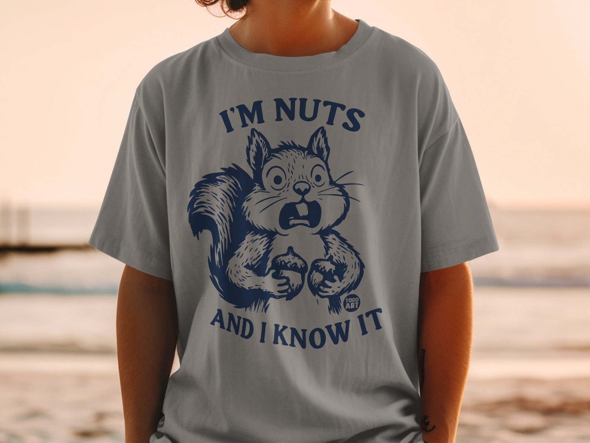 Grey t-shirt with cartoon squirrel holding an acorn, text reads "I'M NUTS AND I KNOW IT".