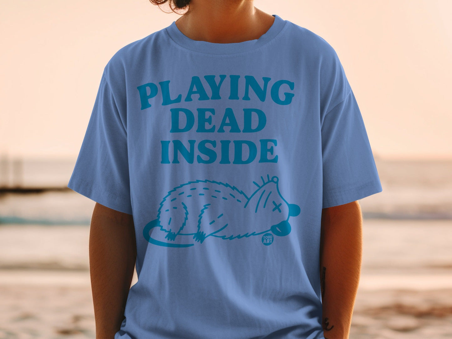 Blue t-shirt with "PLAYING DEAD INSIDE" text and an opossum illustration.