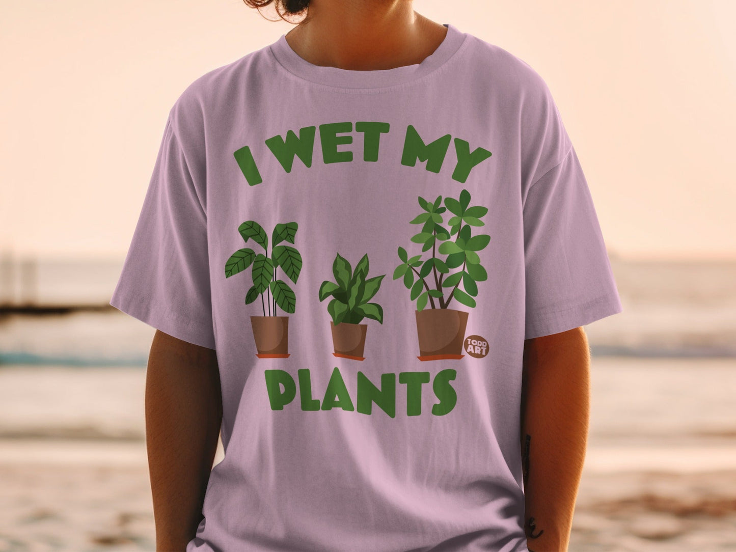 Purple t-shirt with green text "I WET MY PLANTS" and three potted plants.