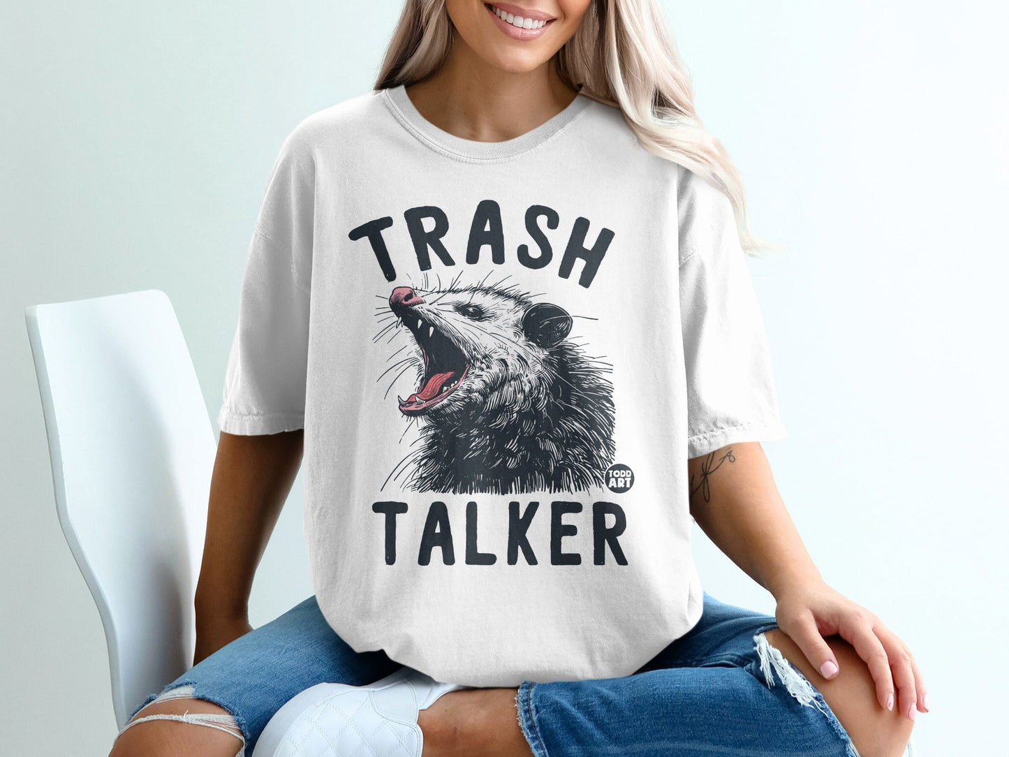 White t-shirt with "TRASH TALKER" text and possum graphic.