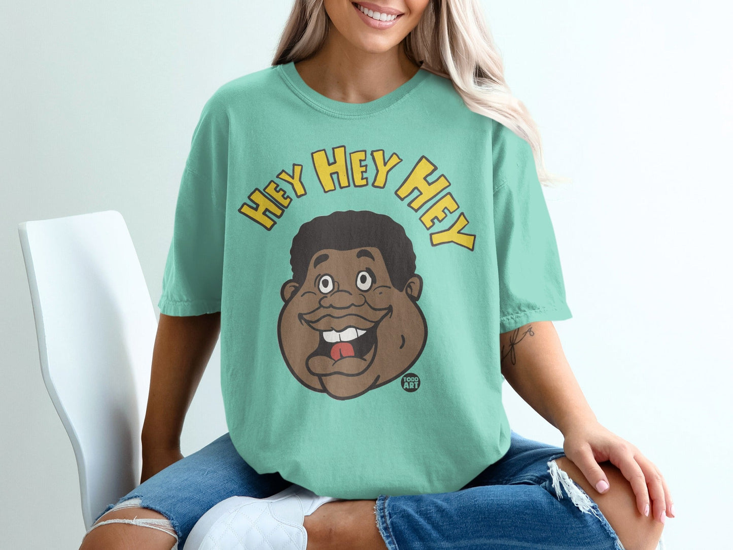 Teal t-shirt with "Hey Hey Hey" and a cartoon face.