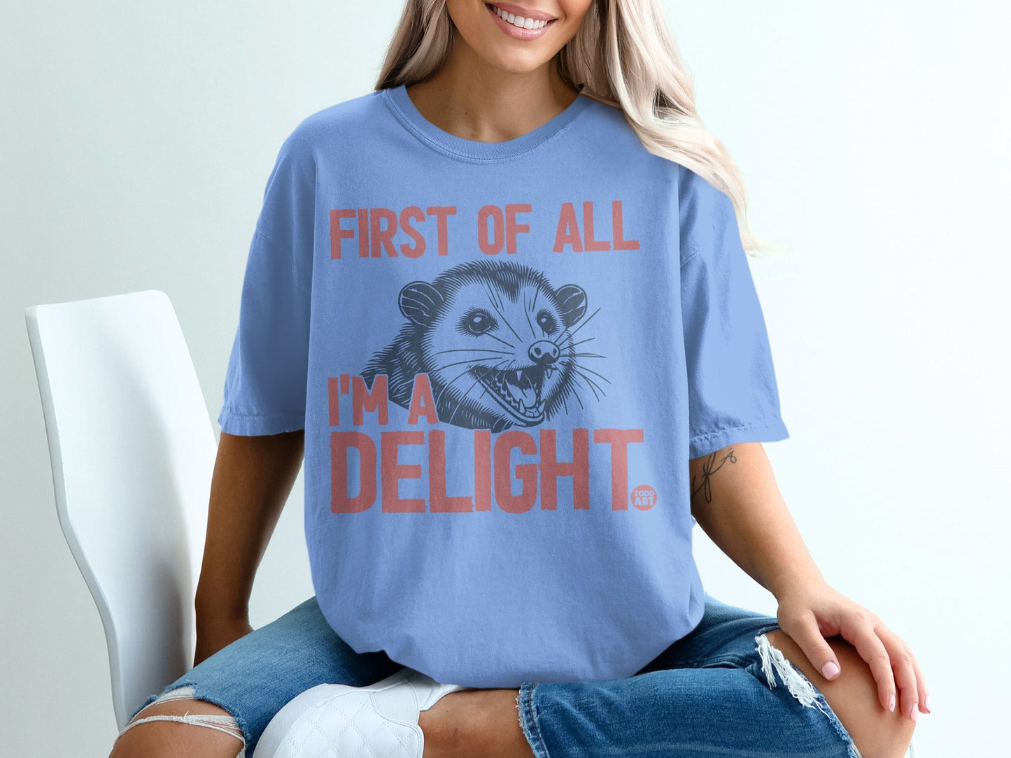 Light blue t-shirt with possum graphic and text "FIRST OF ALL I'M A DELIGHT".