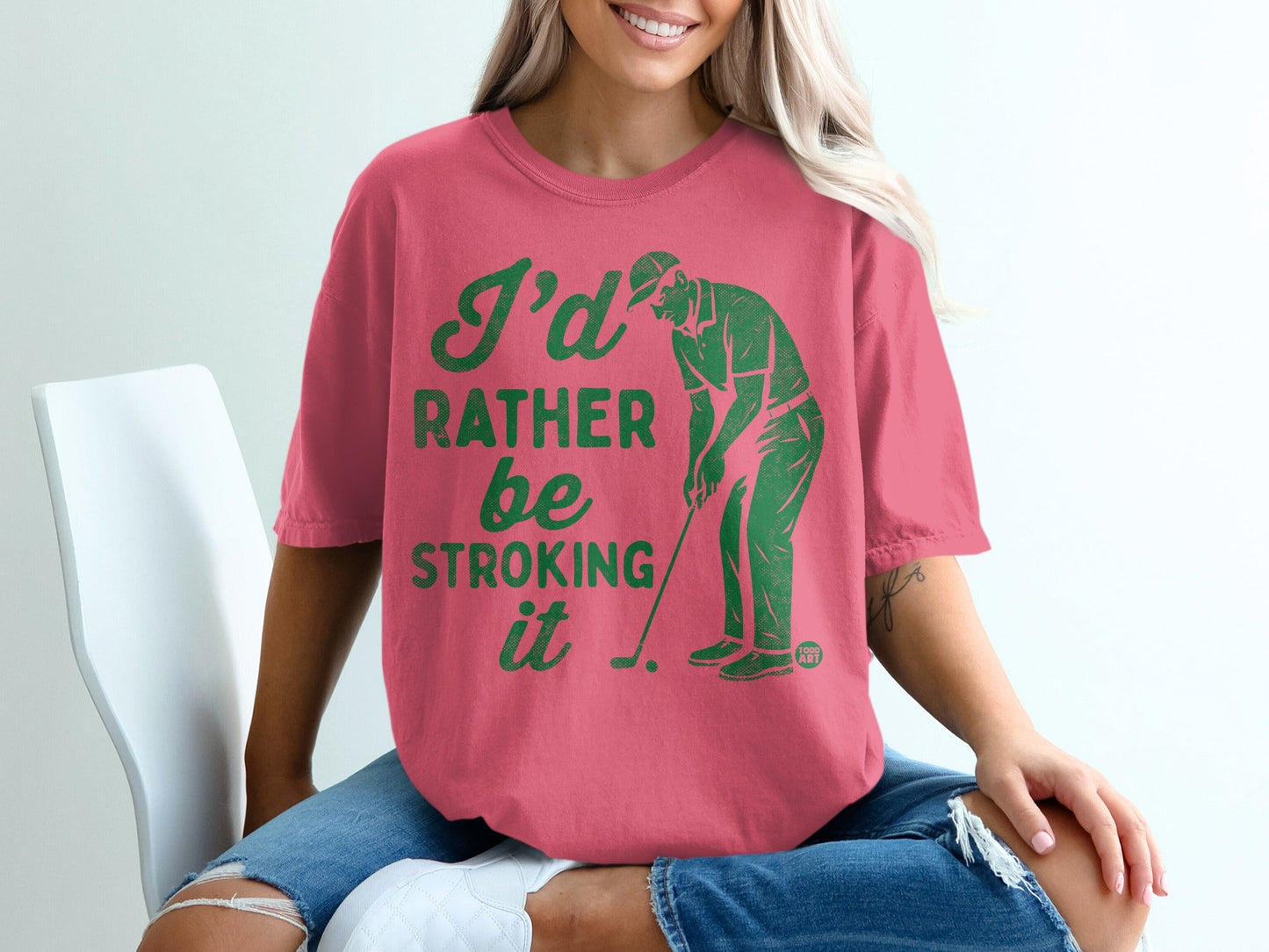 Pink t-shirt with green text and graphic of a golfer.