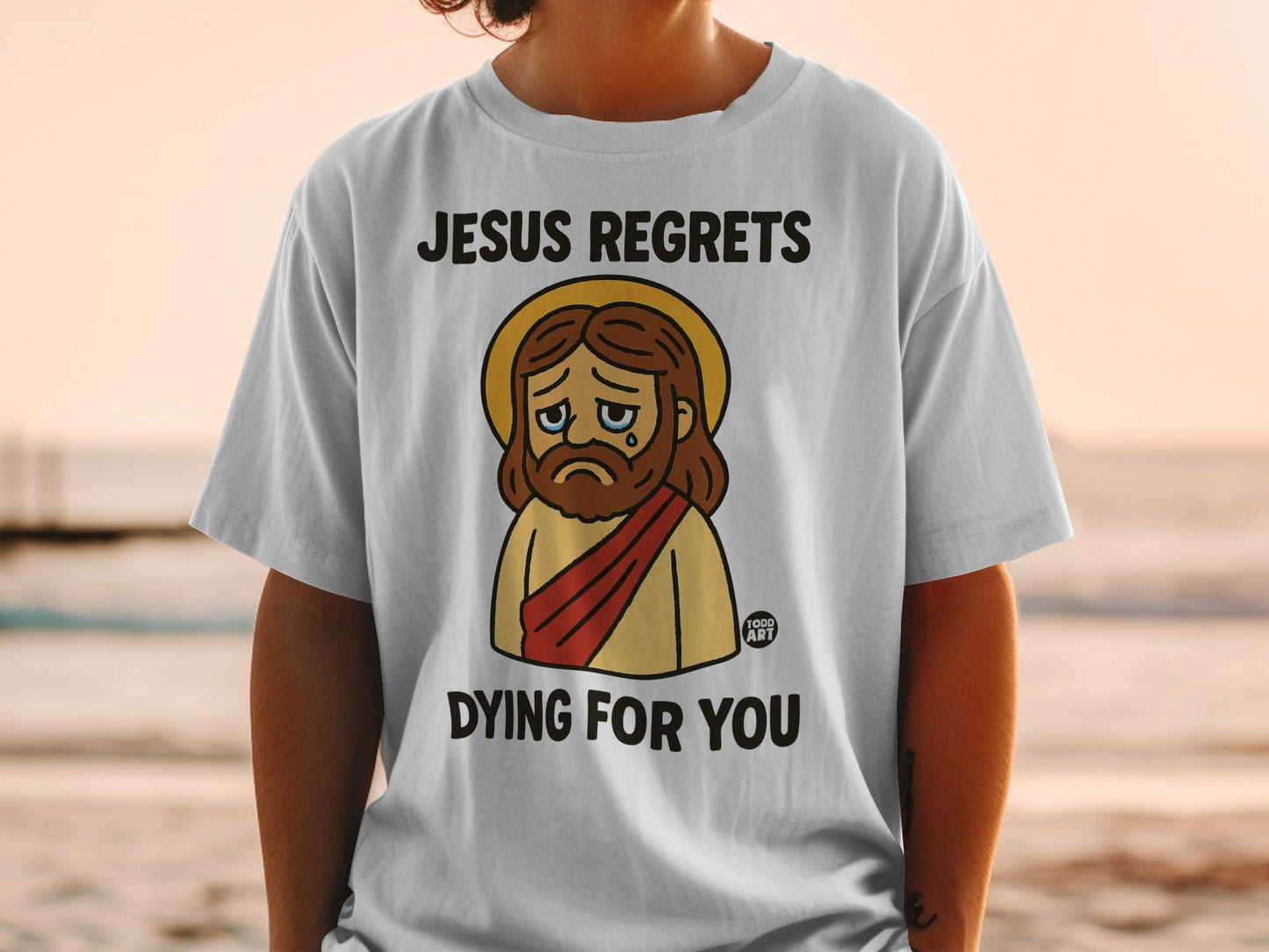 White t-shirt with cartoon Jesus saying "Jesus regrets dying for you"
