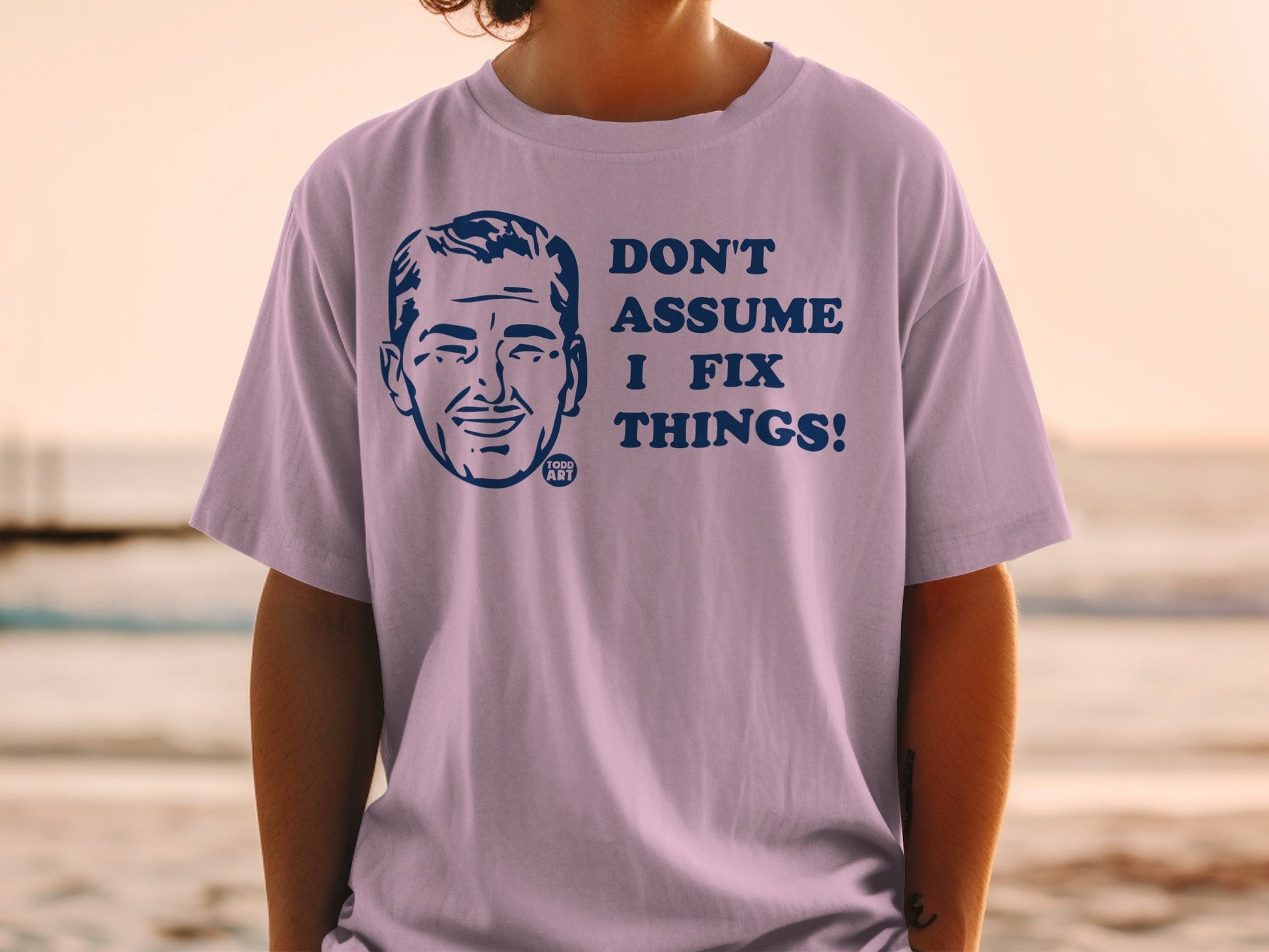 T-shirt with blue cartoon face and "Don't assume I fix things!" text.