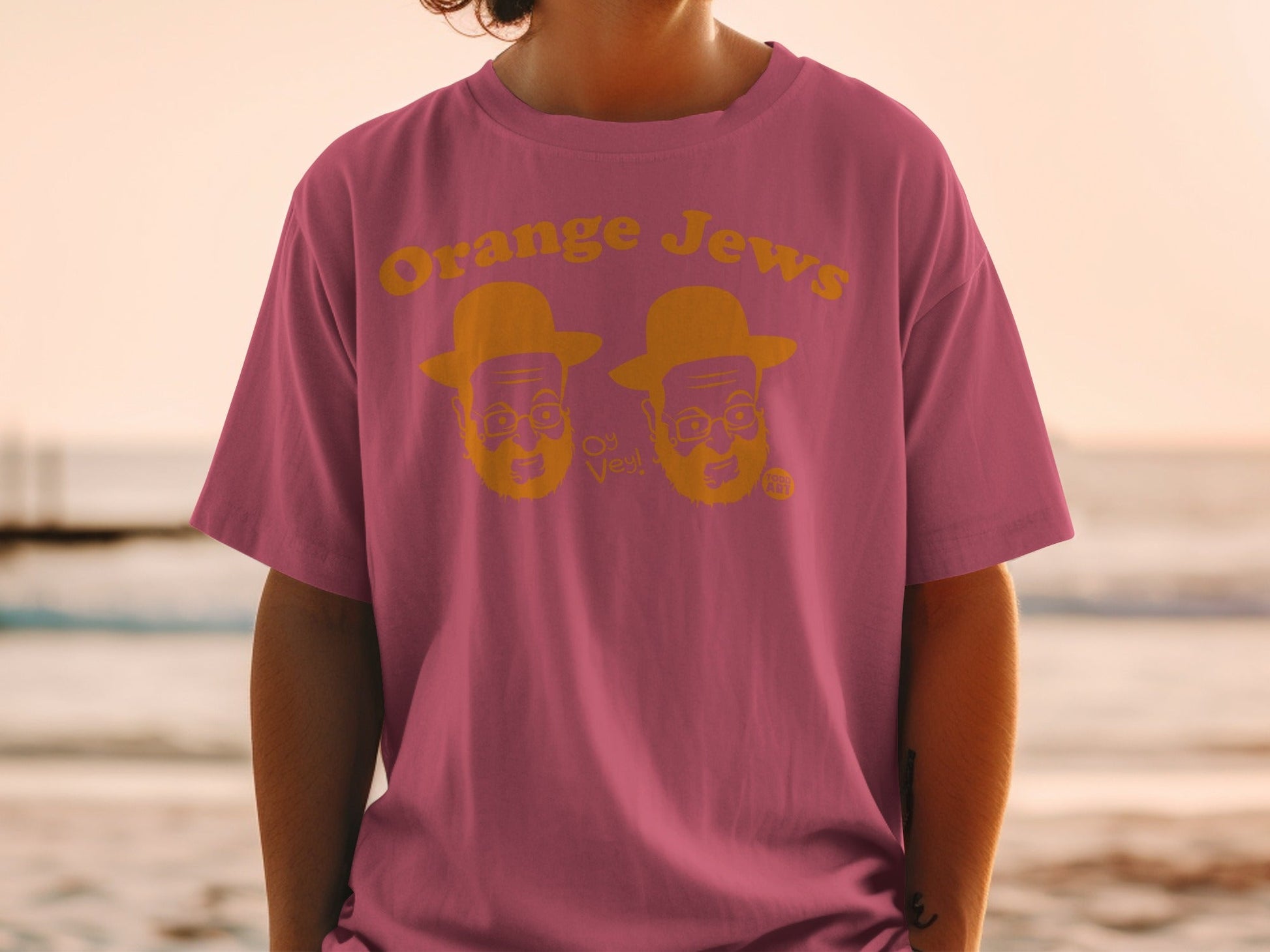 Pink t-shirt with "Orange Jews" text and cartoon faces.