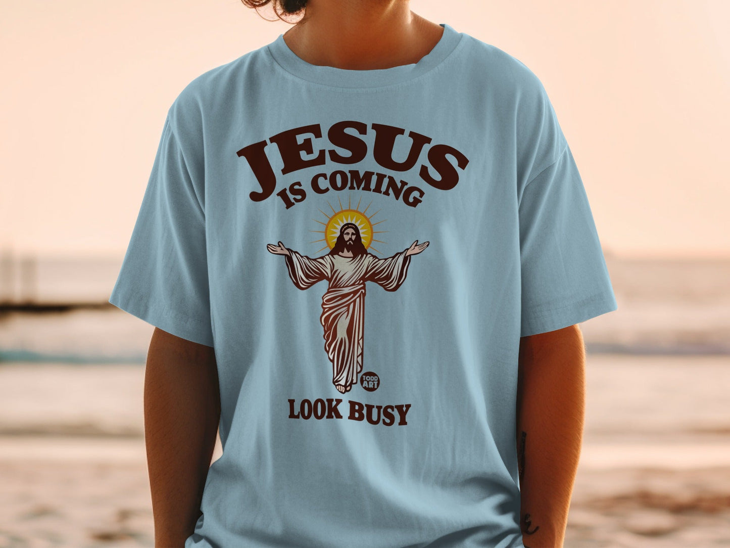 Light blue t-shirt with "JESUS IS COMING LOOK BUSY" text and Jesus illustration.