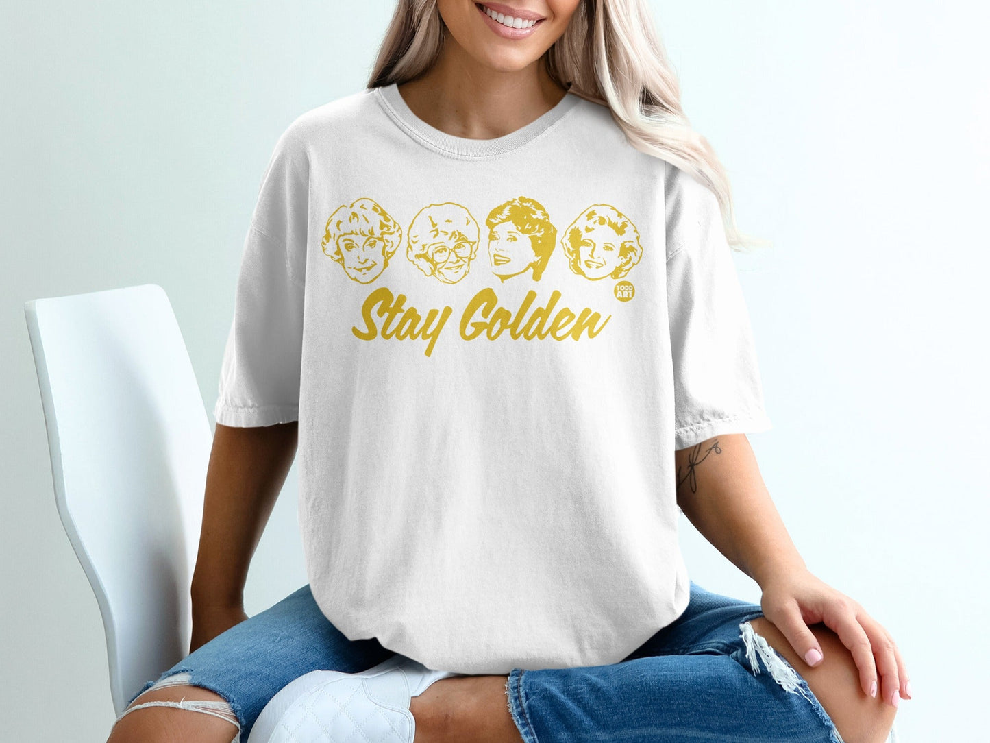 White t-shirt with "Stay Golden" and four cartoon faces of the Golden Girls.