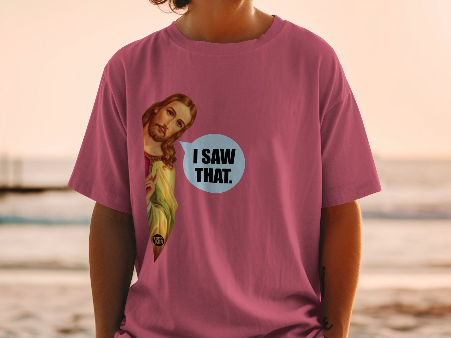 Pink t-shirt with Jesus peeking from the side and "I SAW THAT." text.