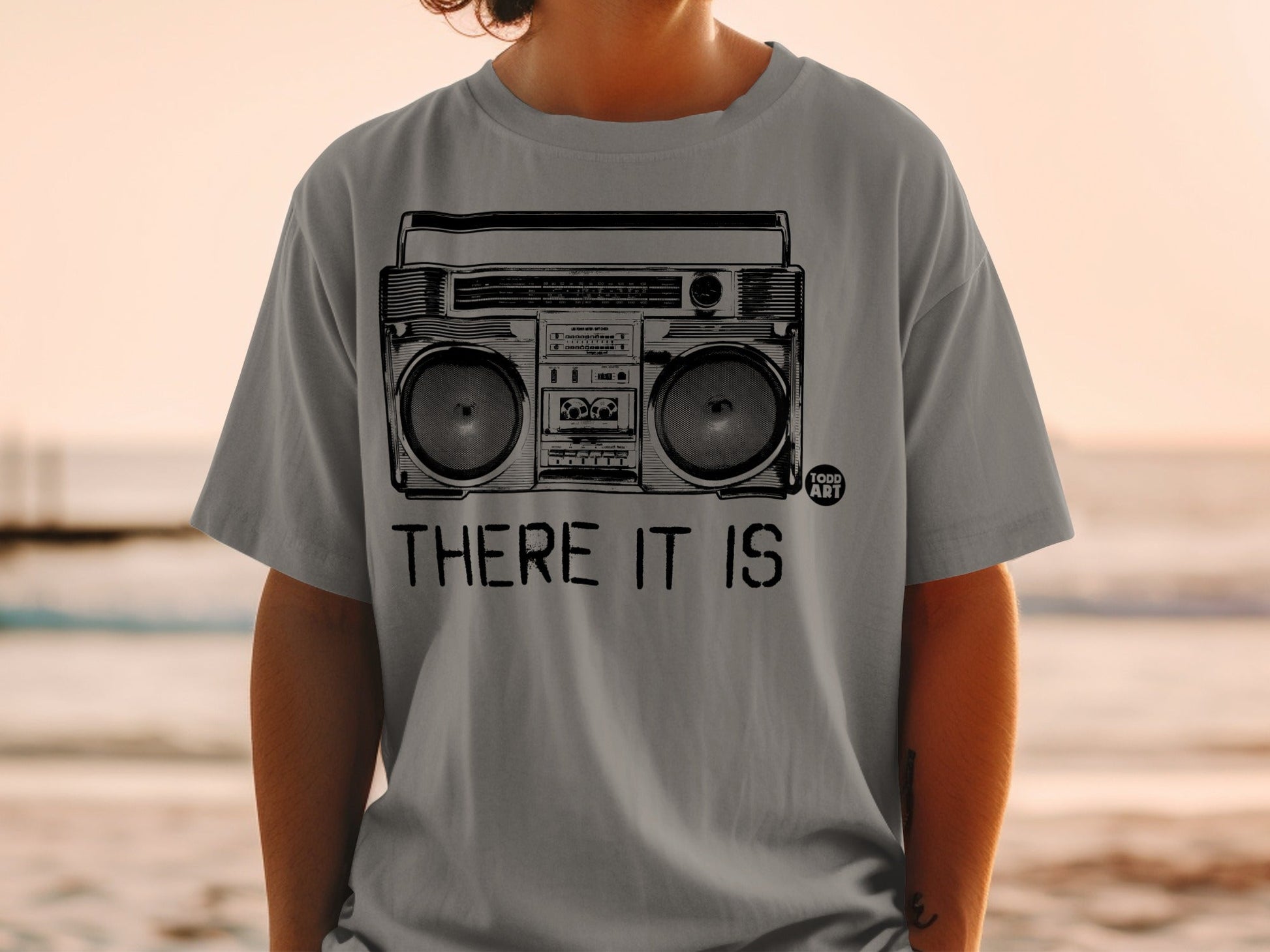 Gray t-shirt with black graphic of a boombox and text "THERE IT IS".