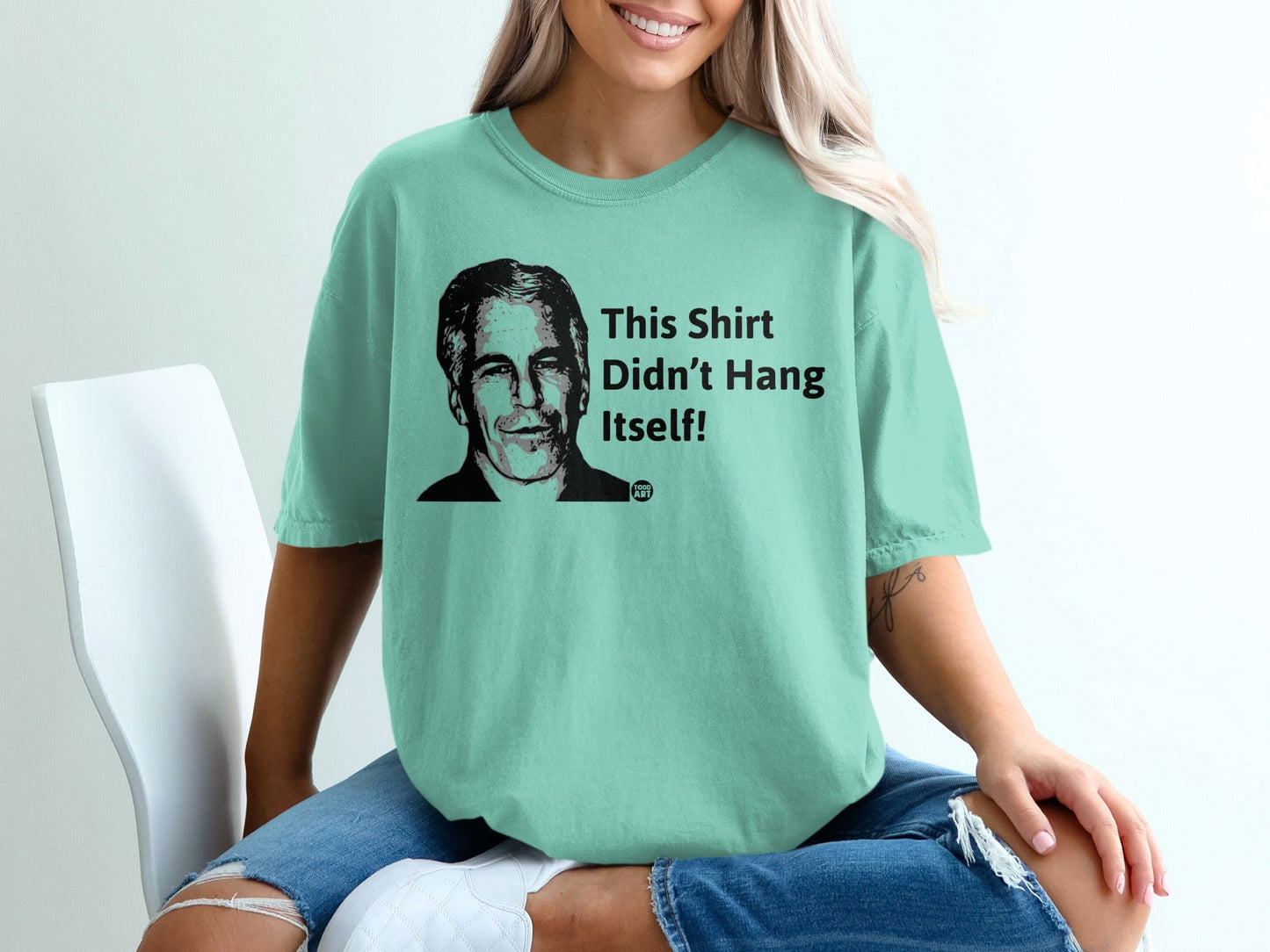 Light teal t-shirt with black graphic text "This Shirt Didn't Hang Itself!"