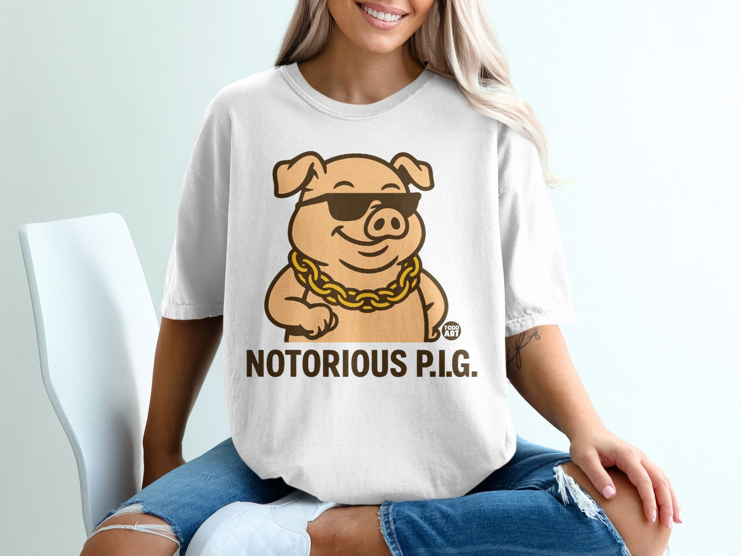 White t-shirt with a cartoon pig wearing sunglasses and a gold chain, text "NOTORIOUS P.I.G."