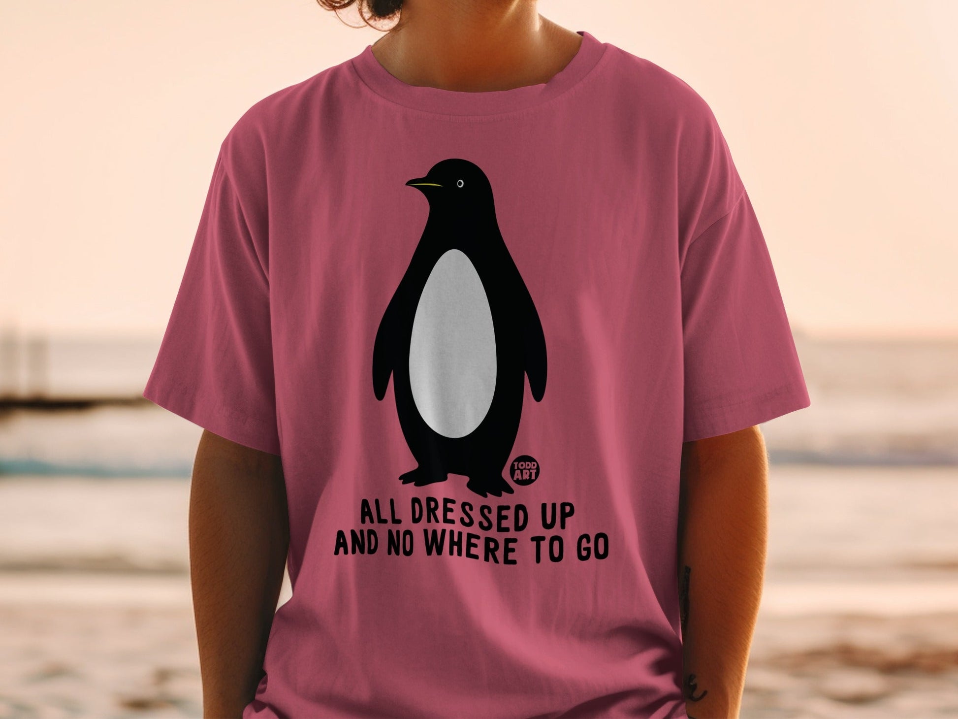 Pink t-shirt with a penguin illustration and text "All Dressed Up And No Where To Go".