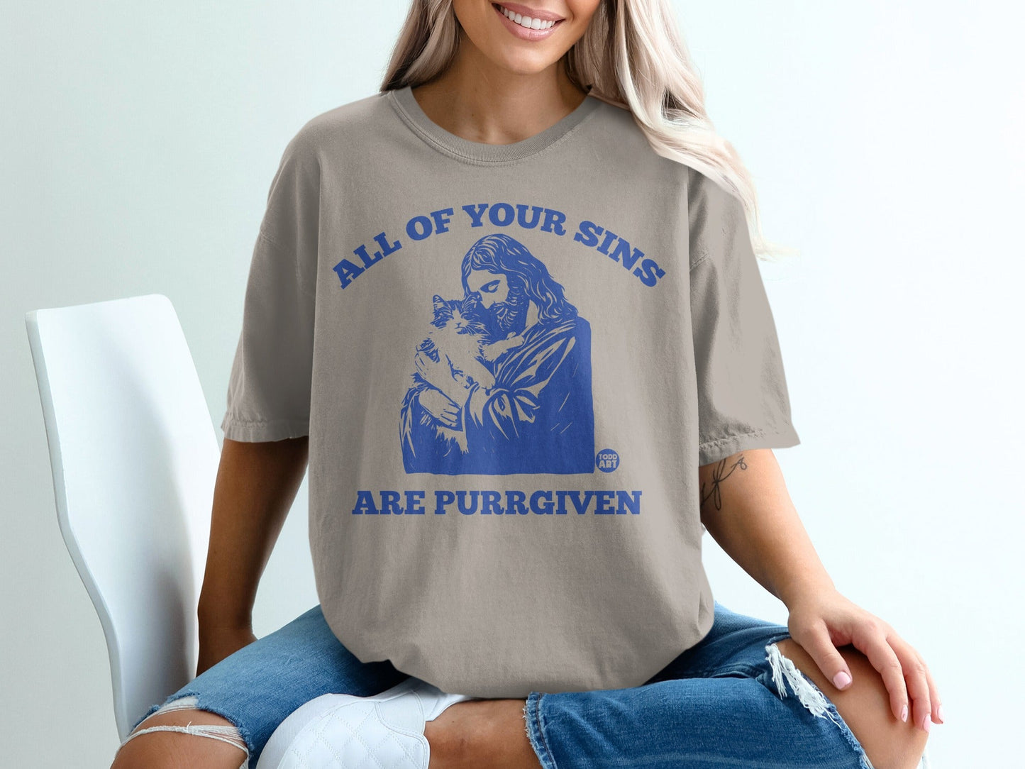 T-shirt with blue text "ALL OF YOUR SINS ARE PURRGIVEN" and graphic of Jesus holding a cat.