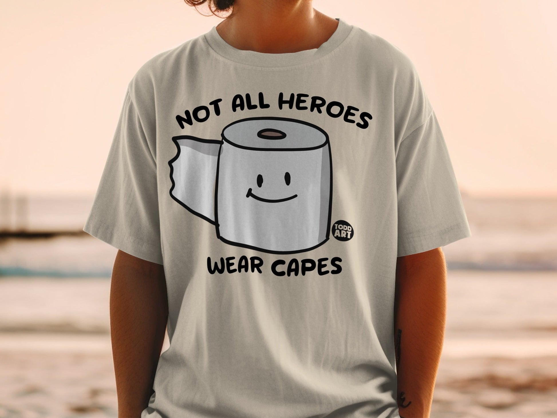T-shirt with toilet paper roll and "Not all heroes wear capes" text.