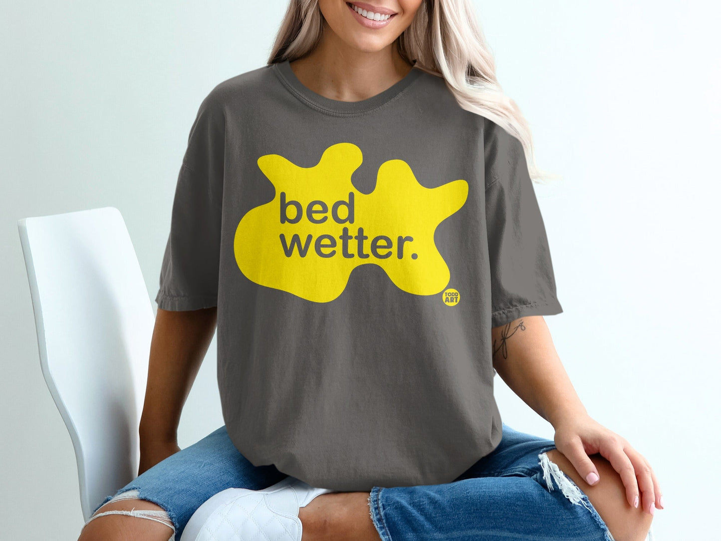 Dark gray t-shirt with yellow "bed wetter." text and small logo.