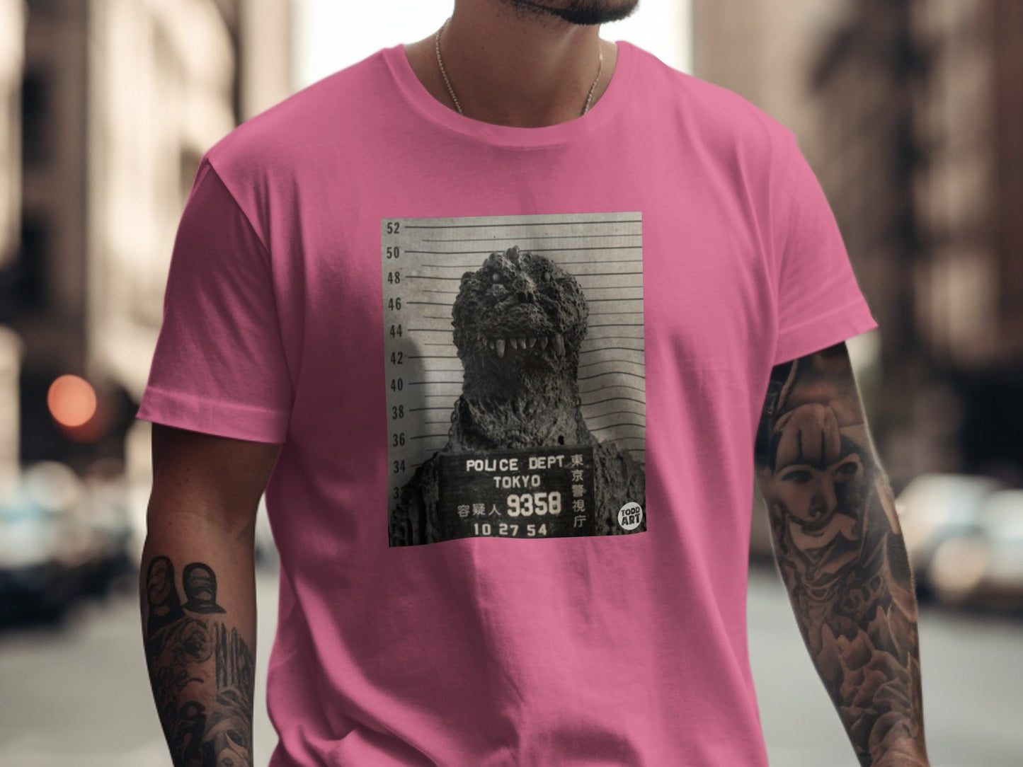 Pink t-shirt featuring a black and white mugshot of Godzilla.