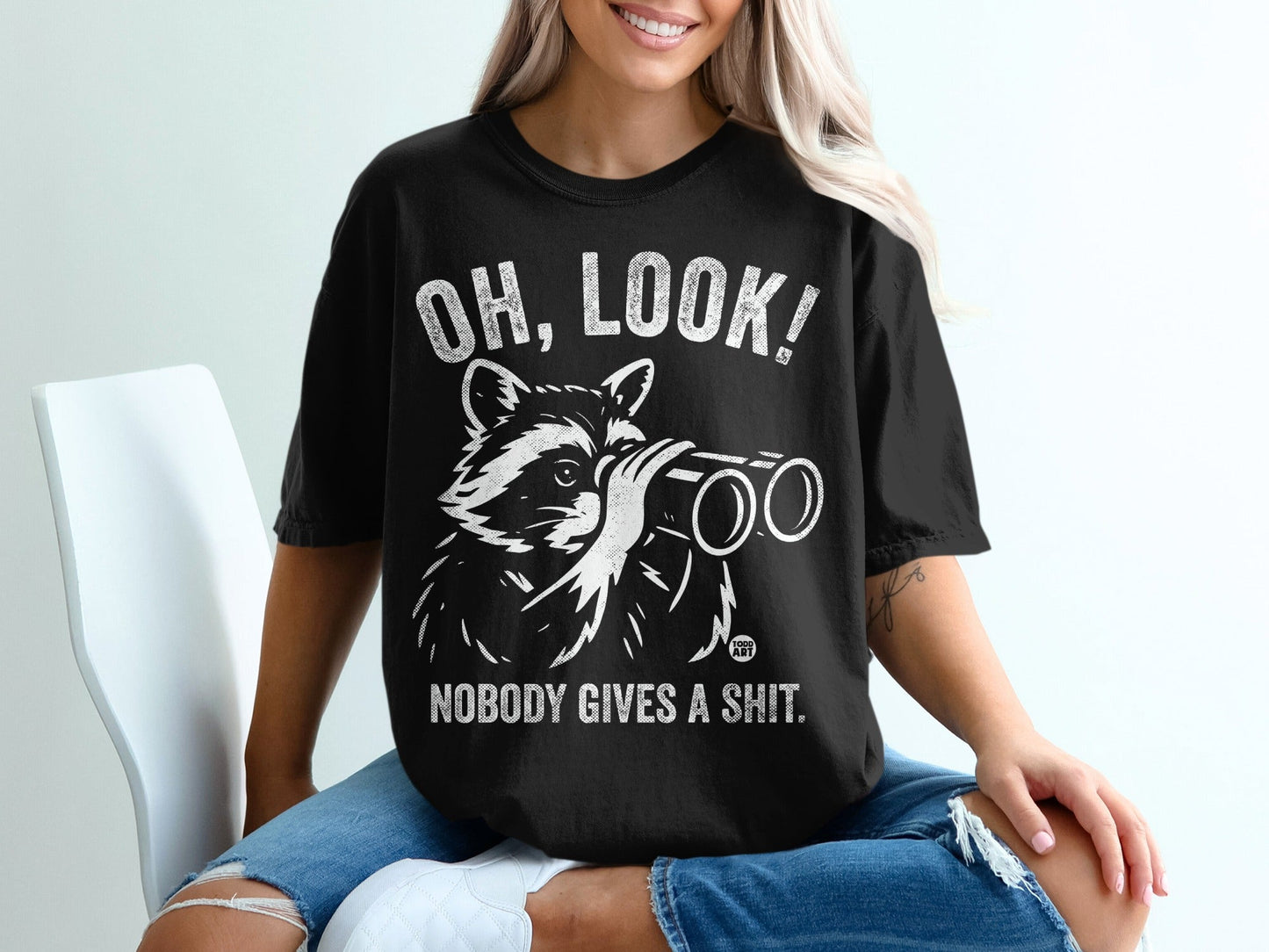 T-shirt with raccoon wearing binoculars and text "OH, LOOK! NOBODY GIVES A SHIT."