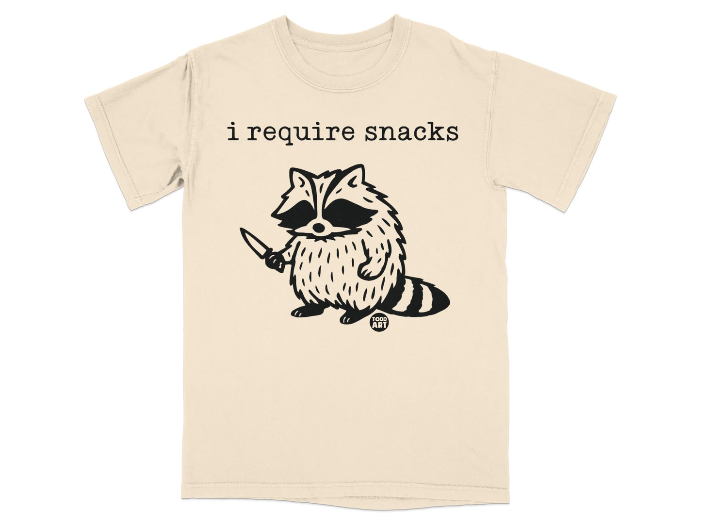 T-shirt with a raccoon holding a knife and the text "i require snacks."