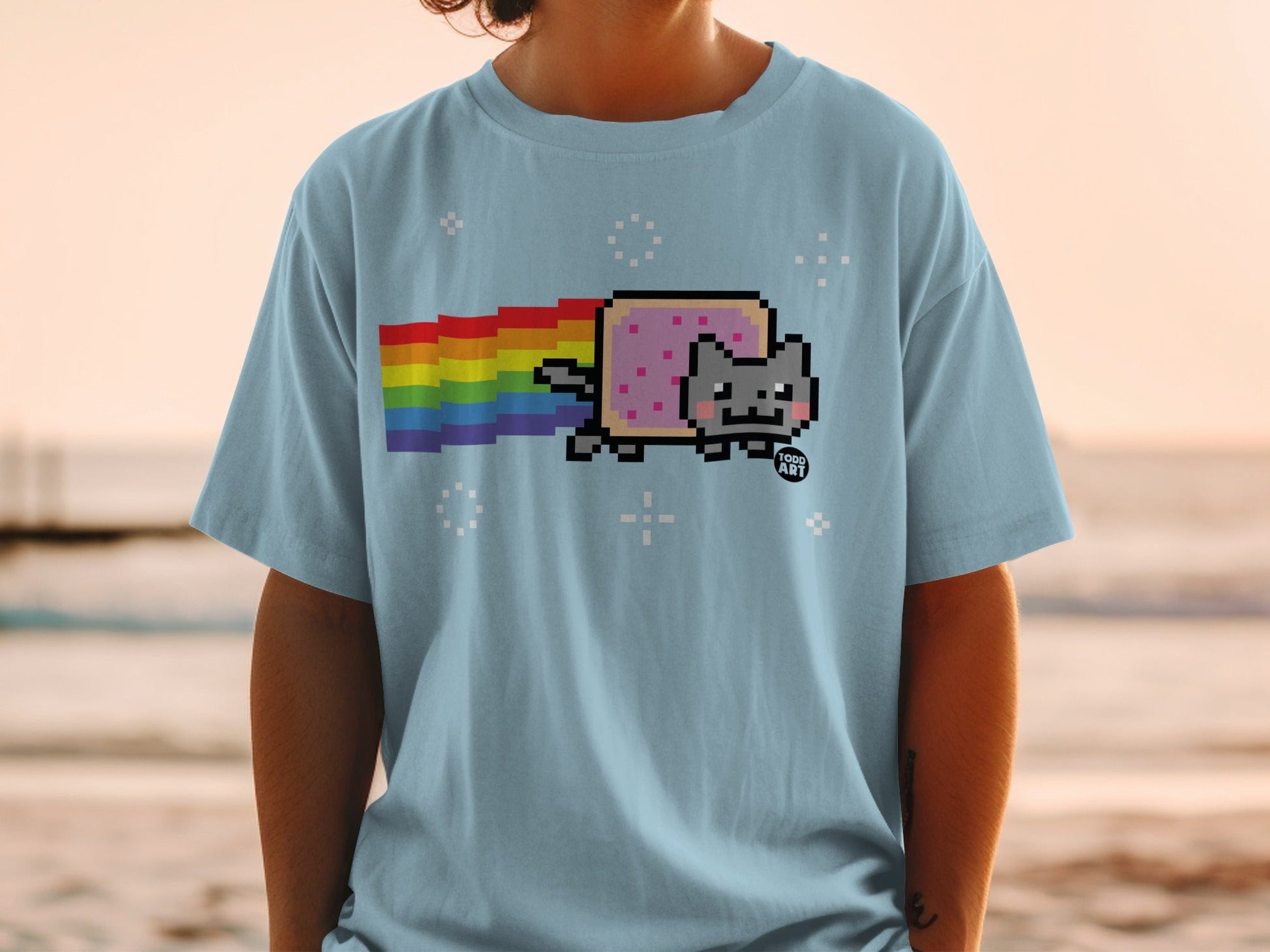 Light blue t-shirt with a pixelated Nyan Cat and rainbow trail.
