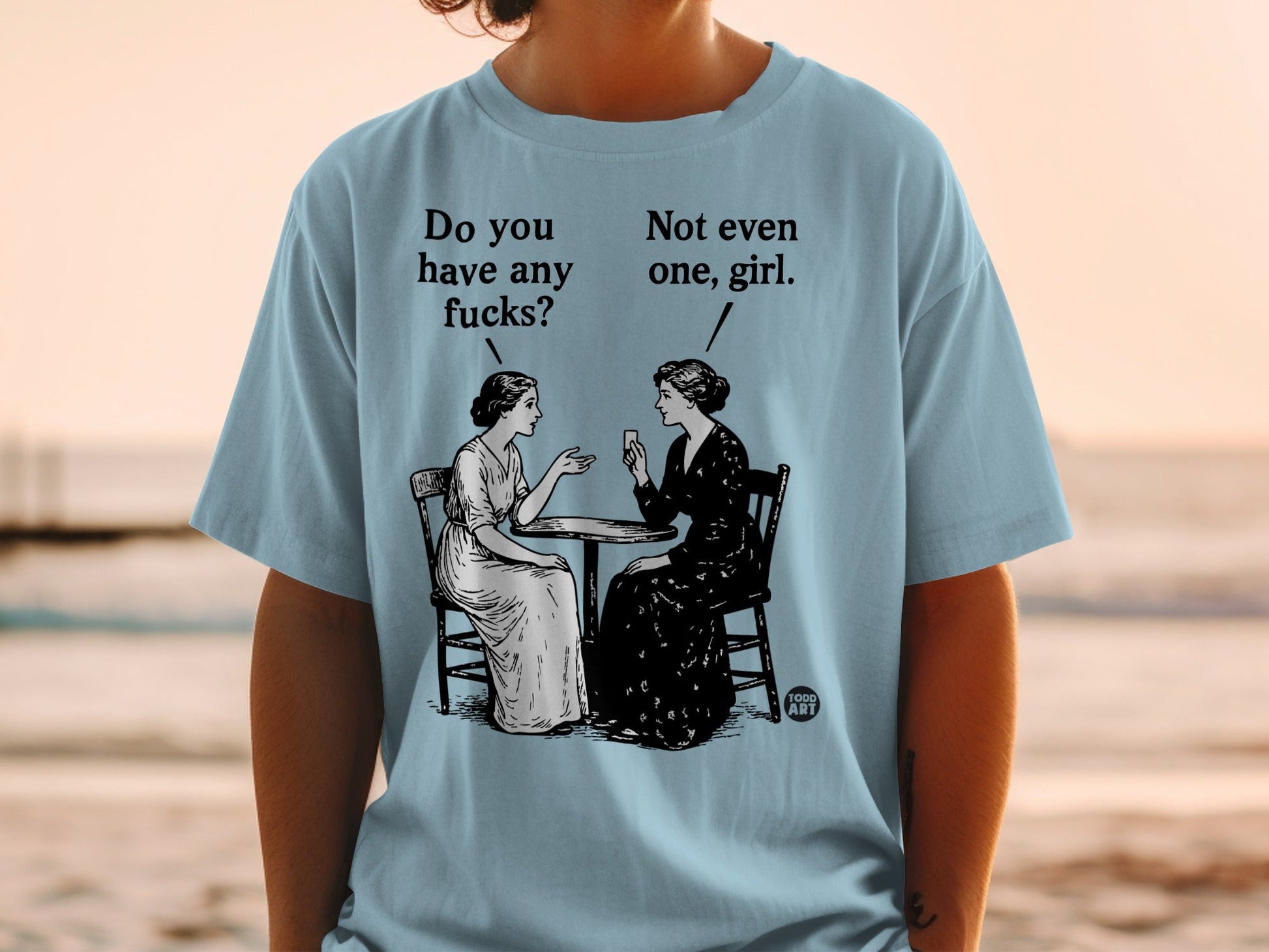 Two women sit at a table, one asks "Do you have any fucks?", the other replies "Not even one, girl."