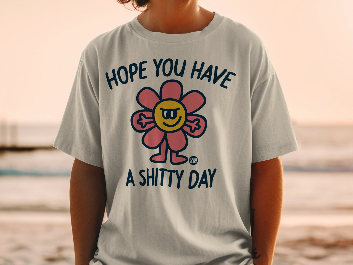 T-shirt with a smiling cartoon flower and text "HOPE YOU HAVE A SHITTY DAY".