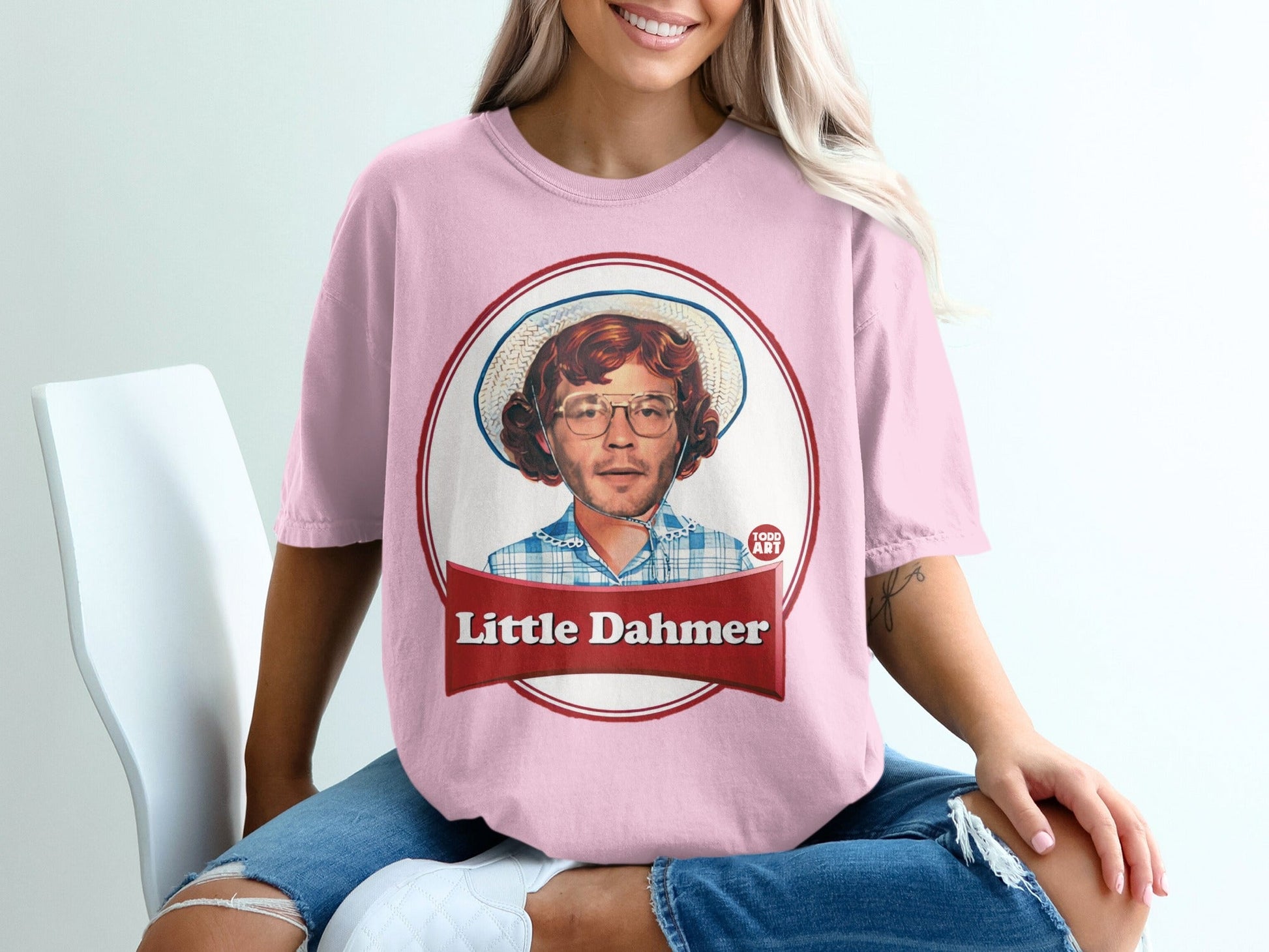 Pink t-shirt with graphic of a man wearing glasses and hat, "Little Dahmer" text.