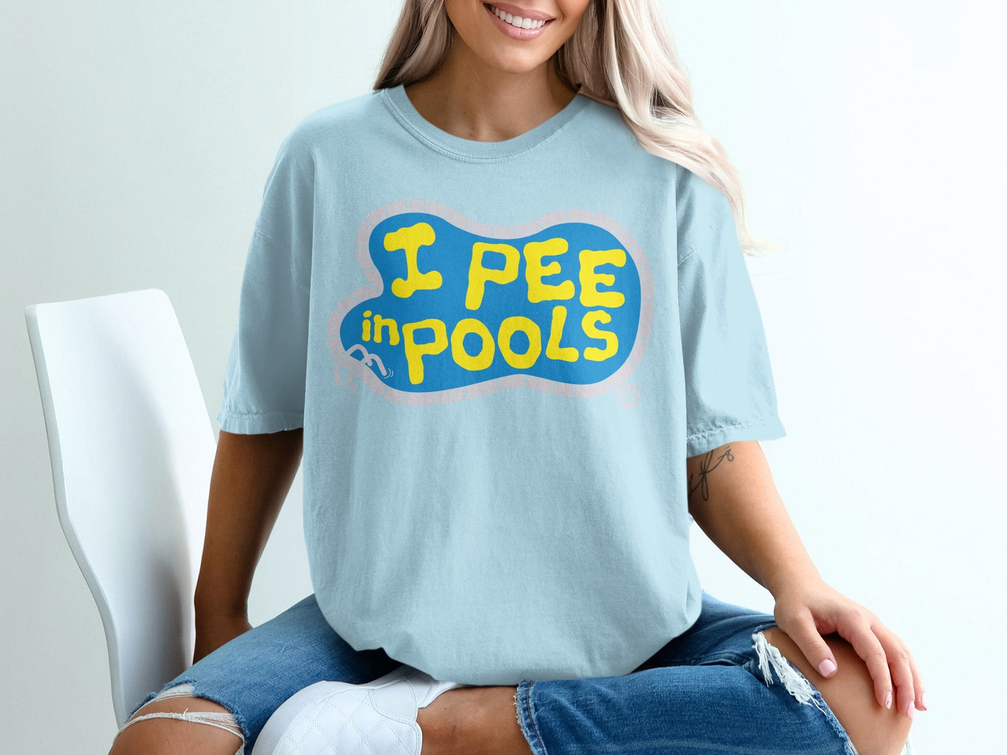 Light blue t-shirt with yellow text reading "I PEE IN POOLS" in a cartoon style.