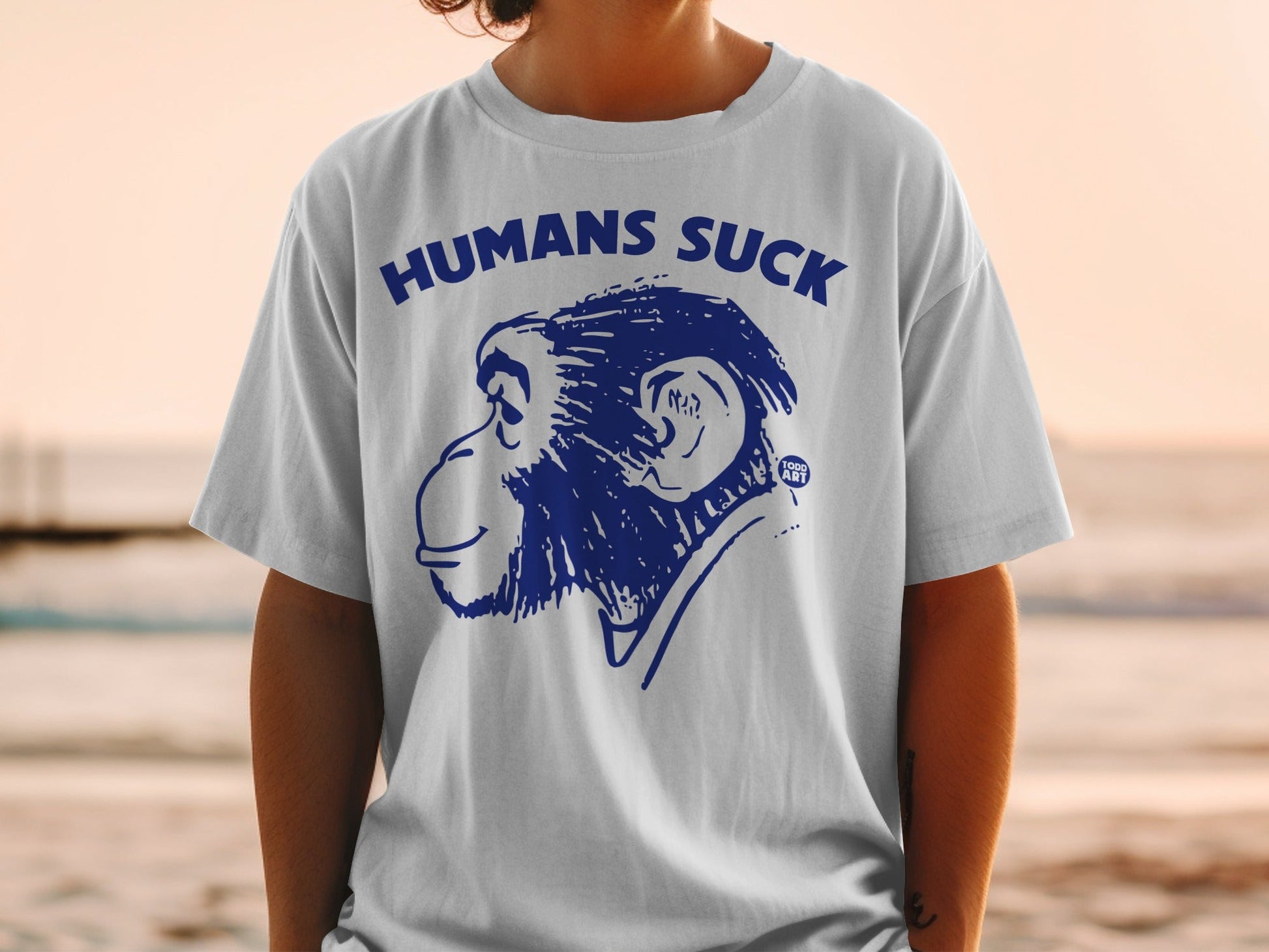 White t-shirt with blue cartoon monkey and text "HUMANS SUCK".
