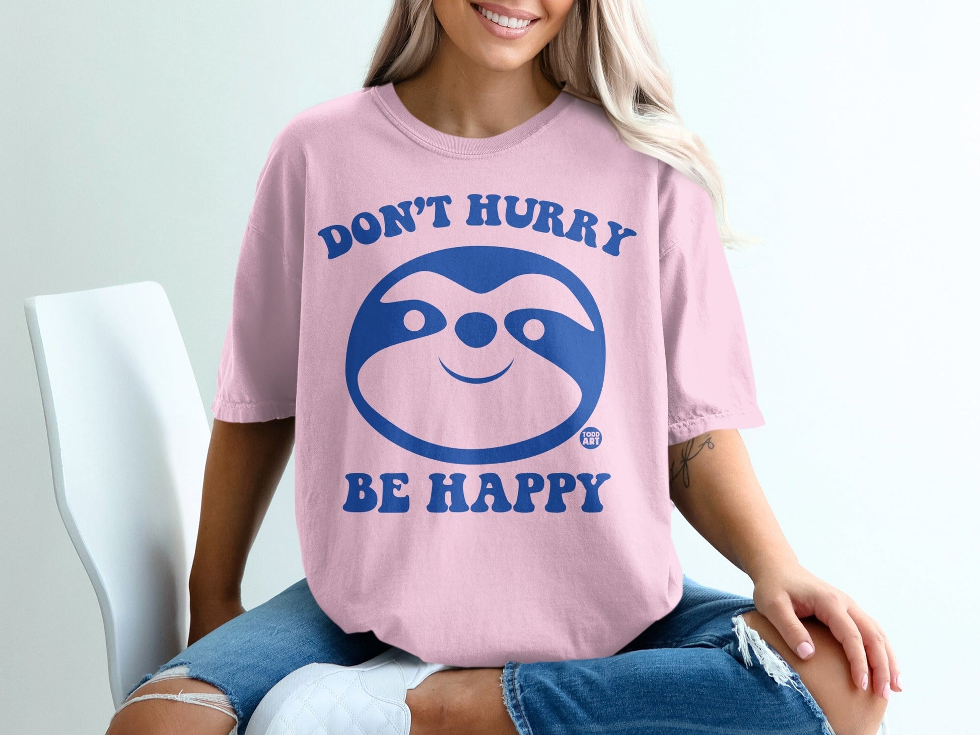 Pink t-shirt with cartoon sloth graphic and text "Don't Hurry Be Happy".