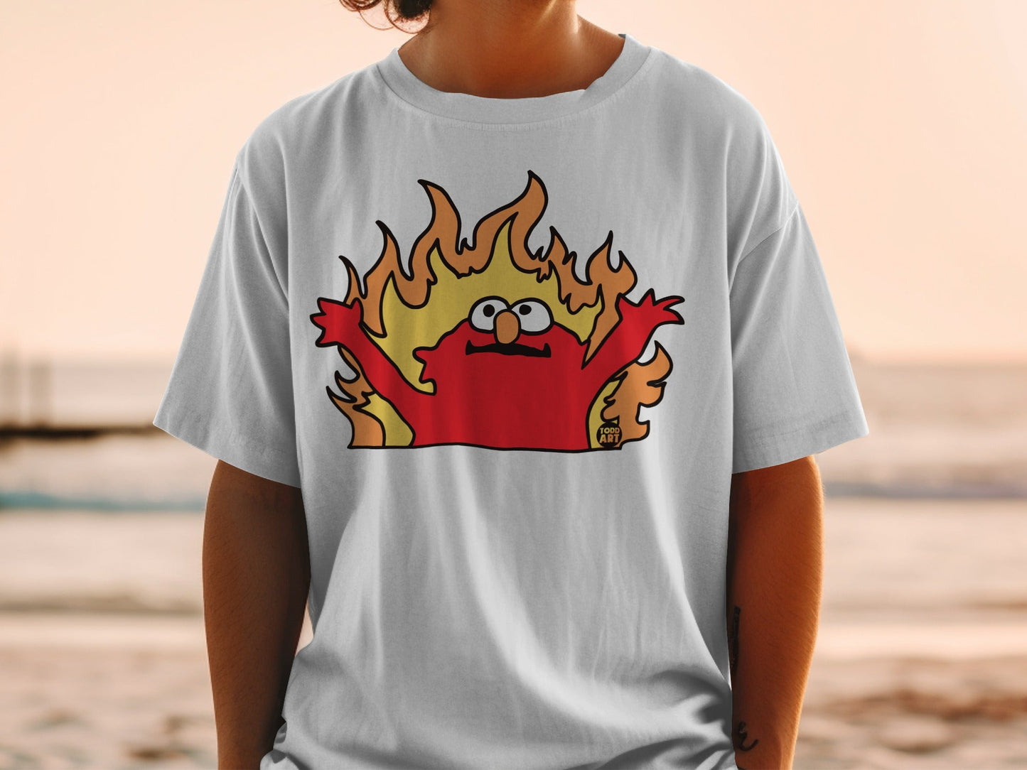 Cartoon character with arms raised in flames on a white t-shirt.