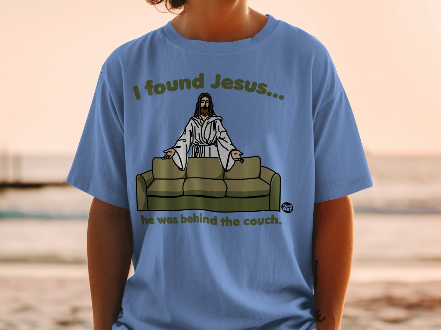 Blue t-shirt with "I found Jesus... he was behind the couch." text.