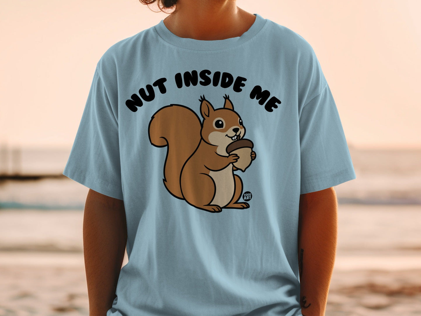 Light blue t-shirt with a cartoon squirrel holding an acorn and the text "NUT INSIDE ME".