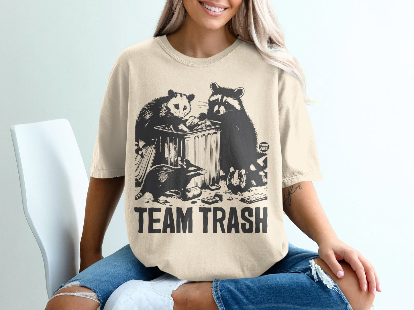 T-shirt graphic with raccoons and opossum digging in trash, "TEAM TRASH" text.