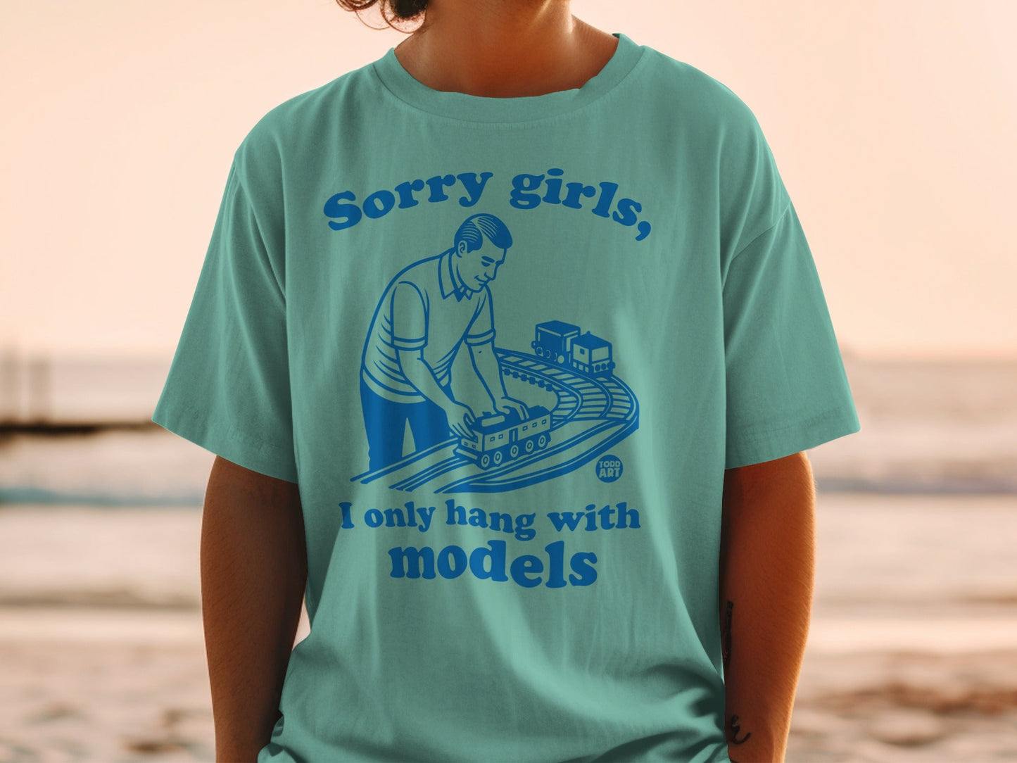 T-shirt with text "Sorry girls, I only hang with models" and illustration of a man with toy train.