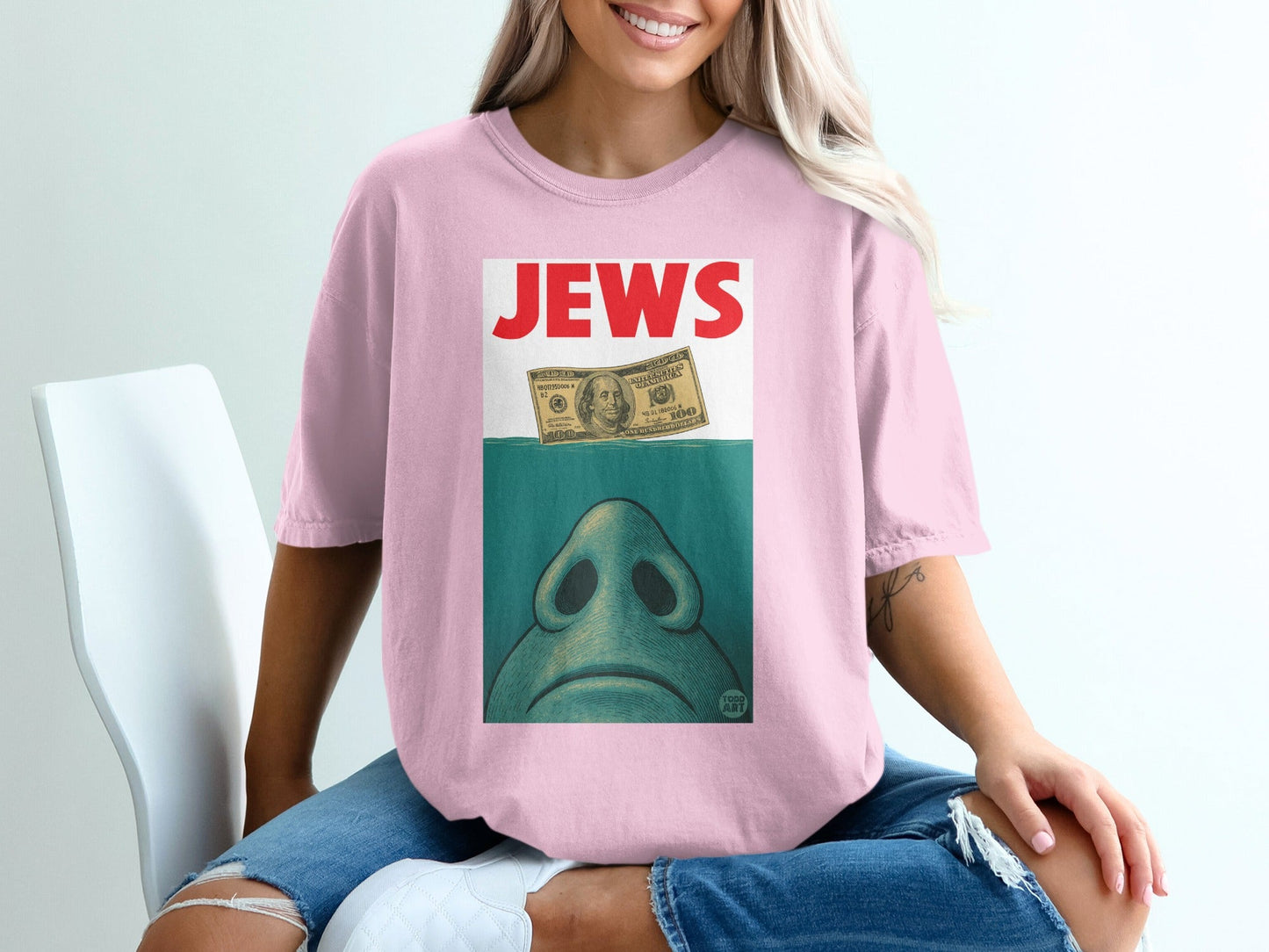 Pink t-shirt with "JEWS" text and illustration of a dollar bill over a face.