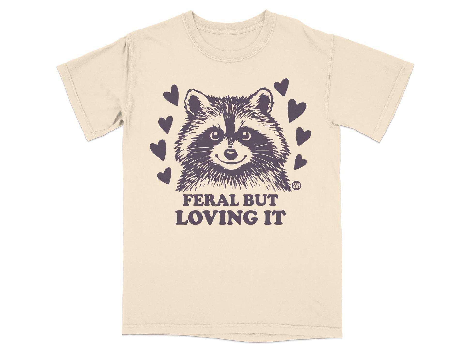 Cream t-shirt with raccoon illustration and text "Feral But Loving It".