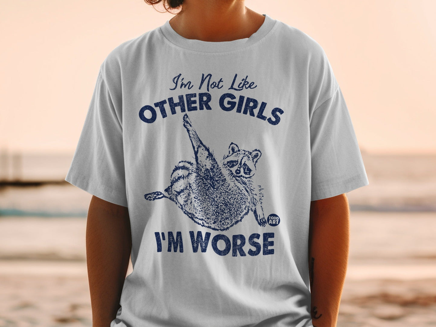 White t-shirt with "I'm Not Like Other Girls I'm Worse" and a raccoon graphic.