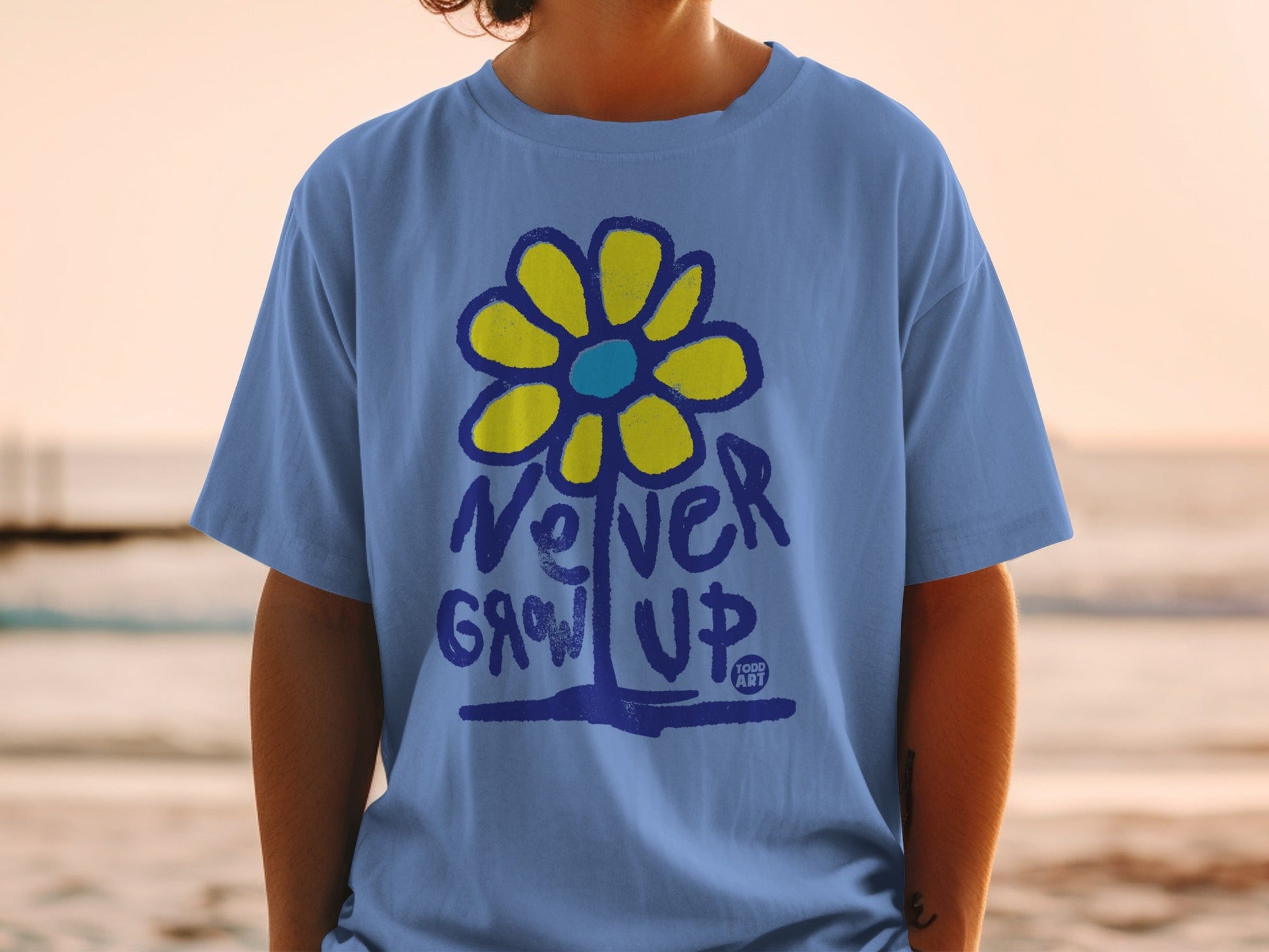 Blue t-shirt with yellow flower graphic and "Never Grow Up" text.
