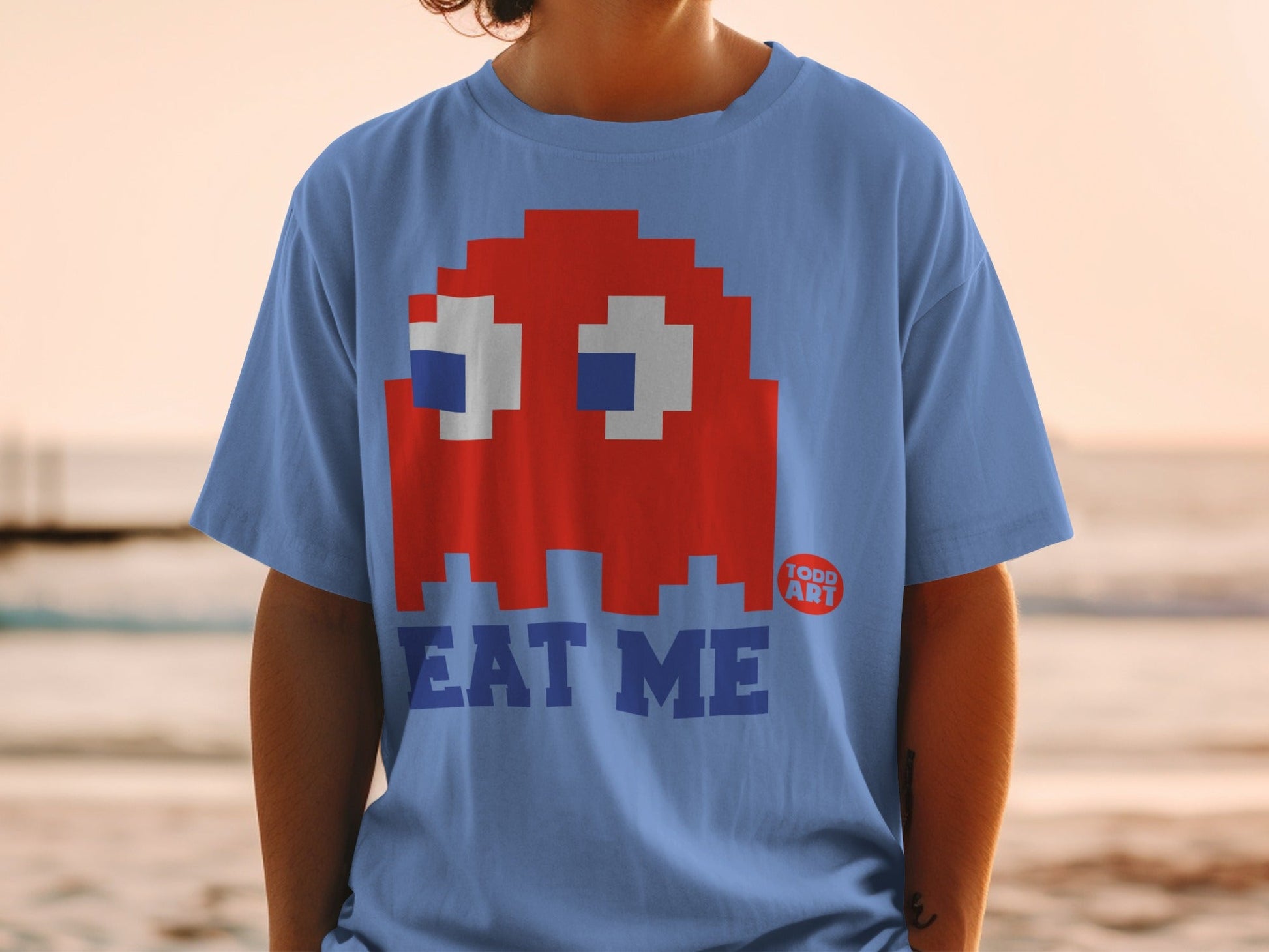 Blue t-shirt with Pac-Man ghost and "EAT ME" text.