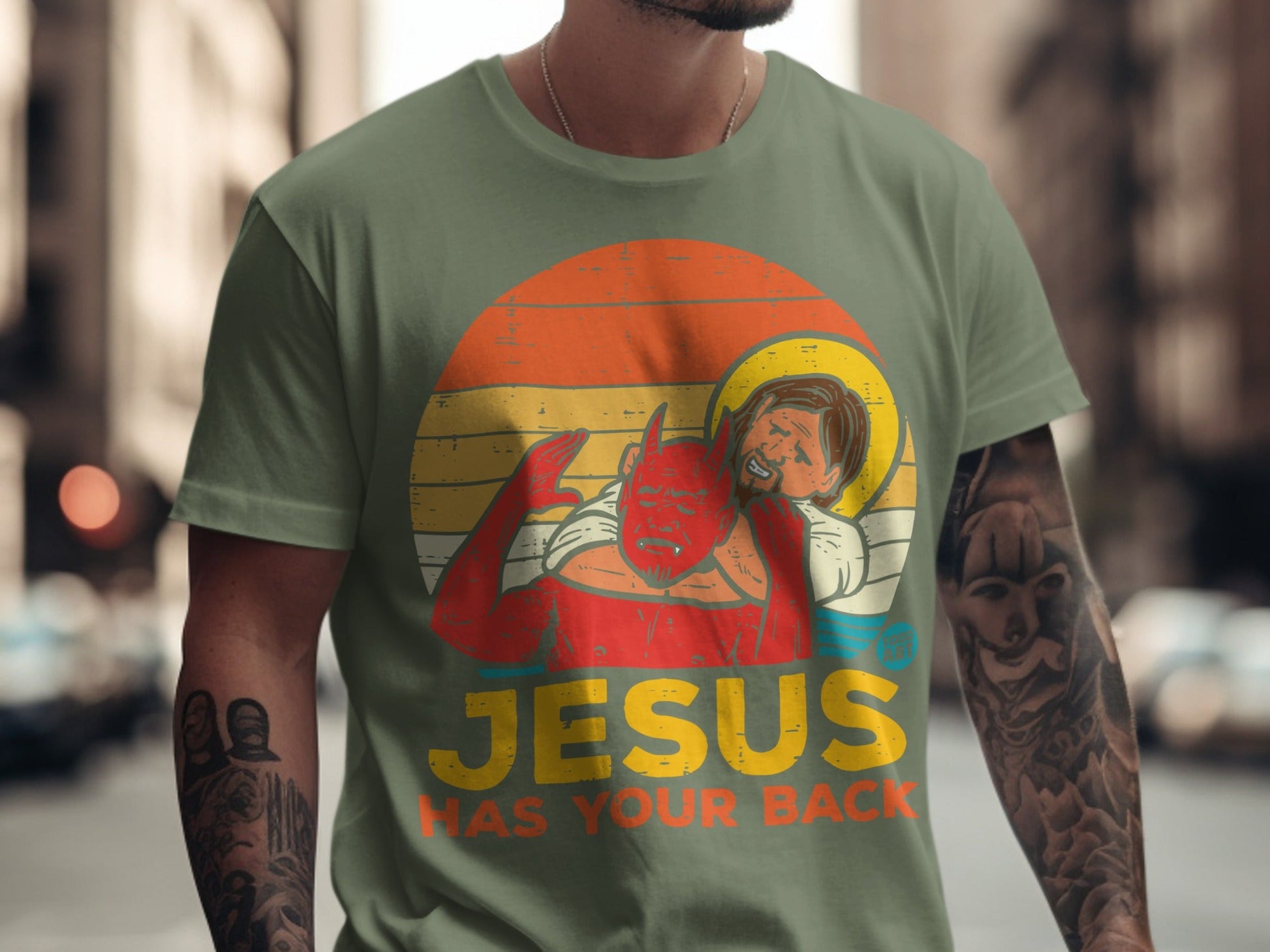 Green t-shirt with "Jesus Has Your Back" text and devil holding Jesus.
