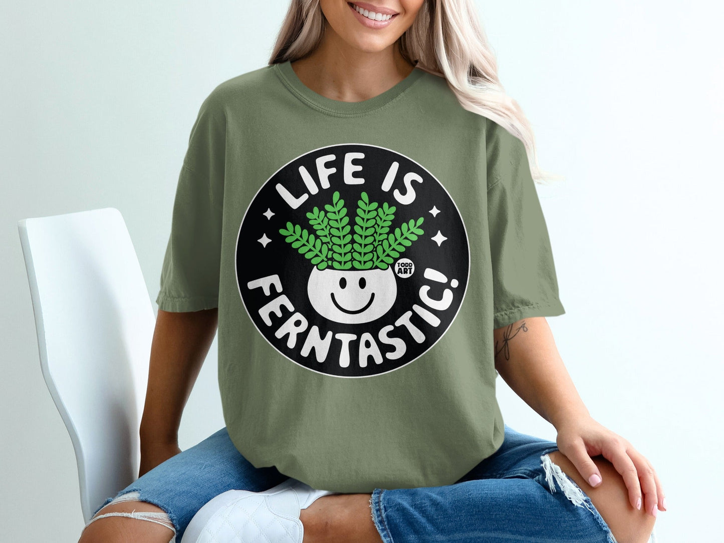 Green t-shirt with black circle graphic: "LIFE IS FERNTASIC!" smiling plant face.