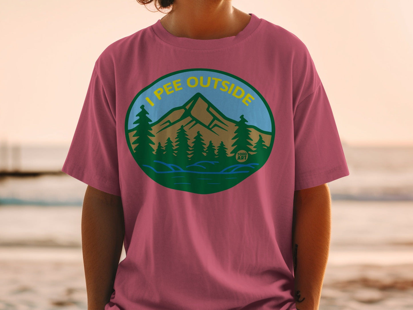 T-shirt featuring a circular graphic of mountains, trees, and "I pee outside" text.