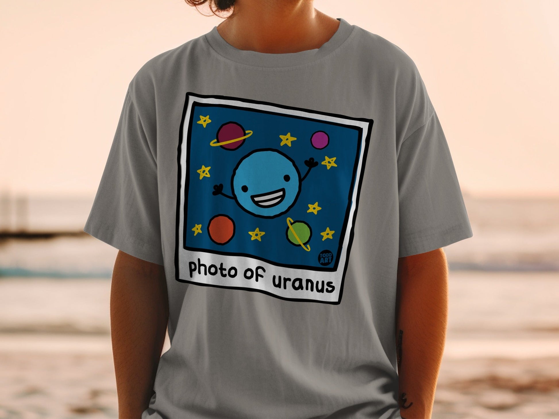 T-shirt with cartoon illustration of a smiling planet Uranus and stars.