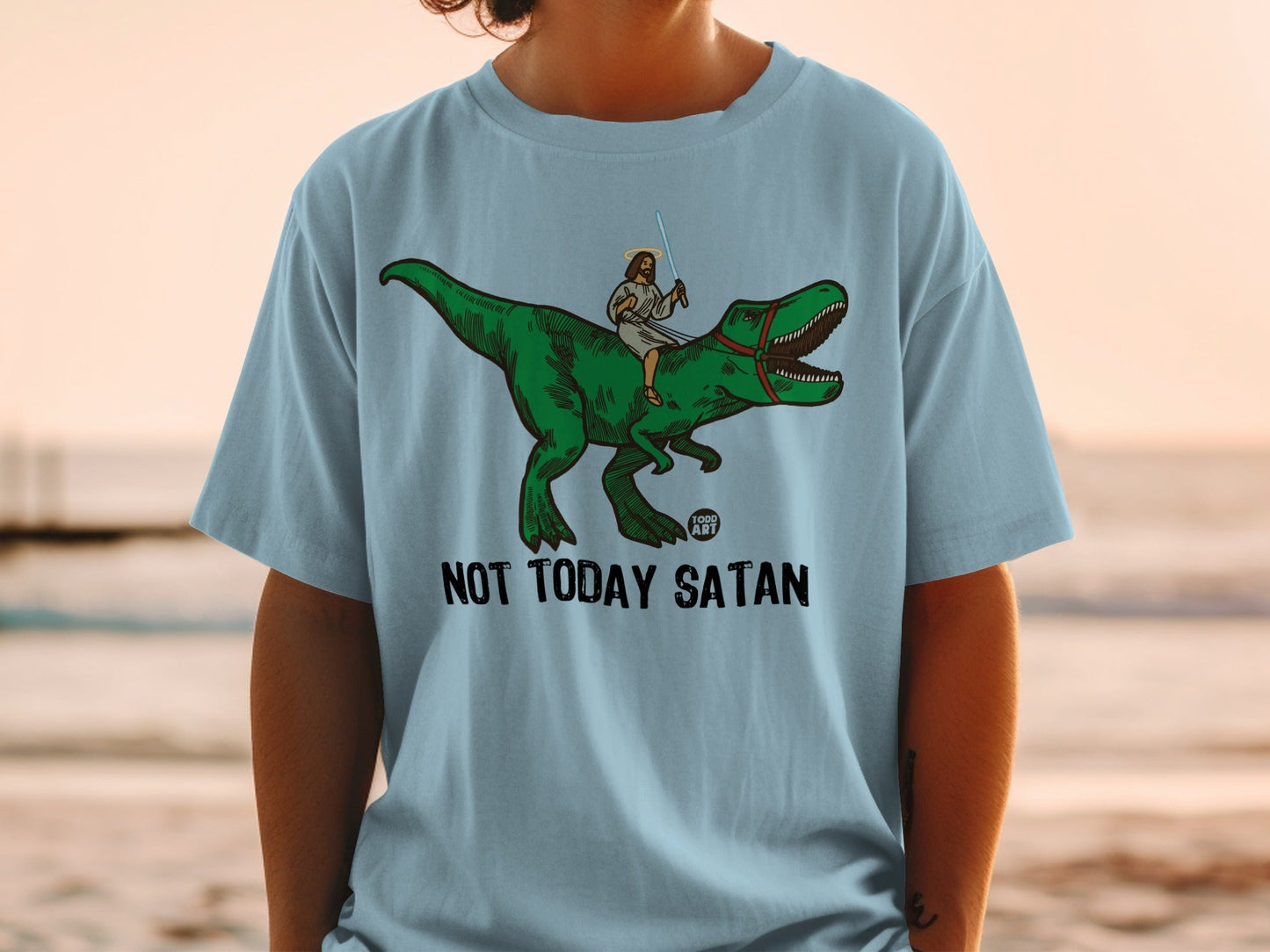 Light blue t-shirt with Jesus riding a dinosaur, "Not Today Satan" text.