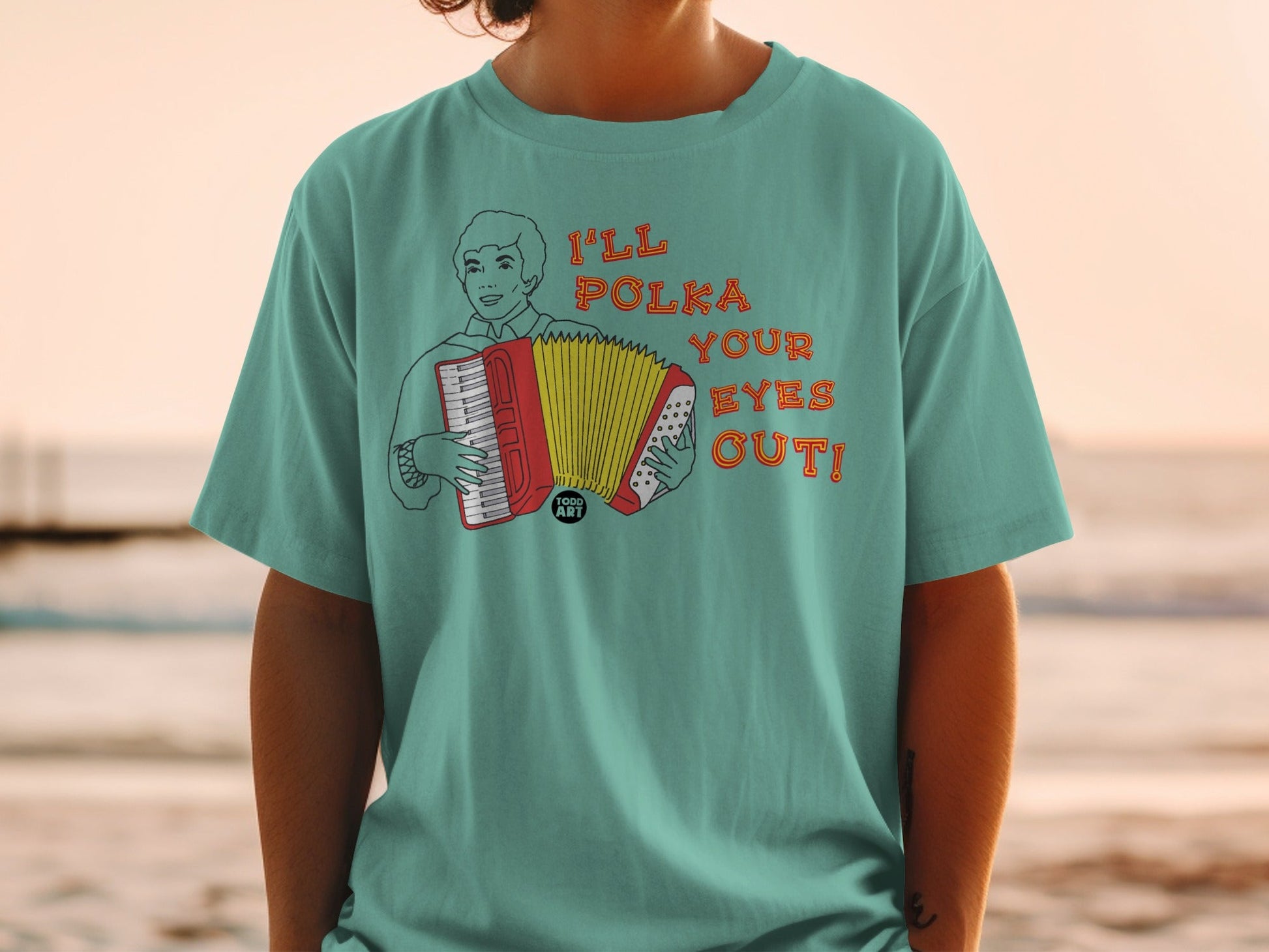 T-shirt with cartoon man playing accordion, text "I'LL POLKA YOUR EYES OUT!".