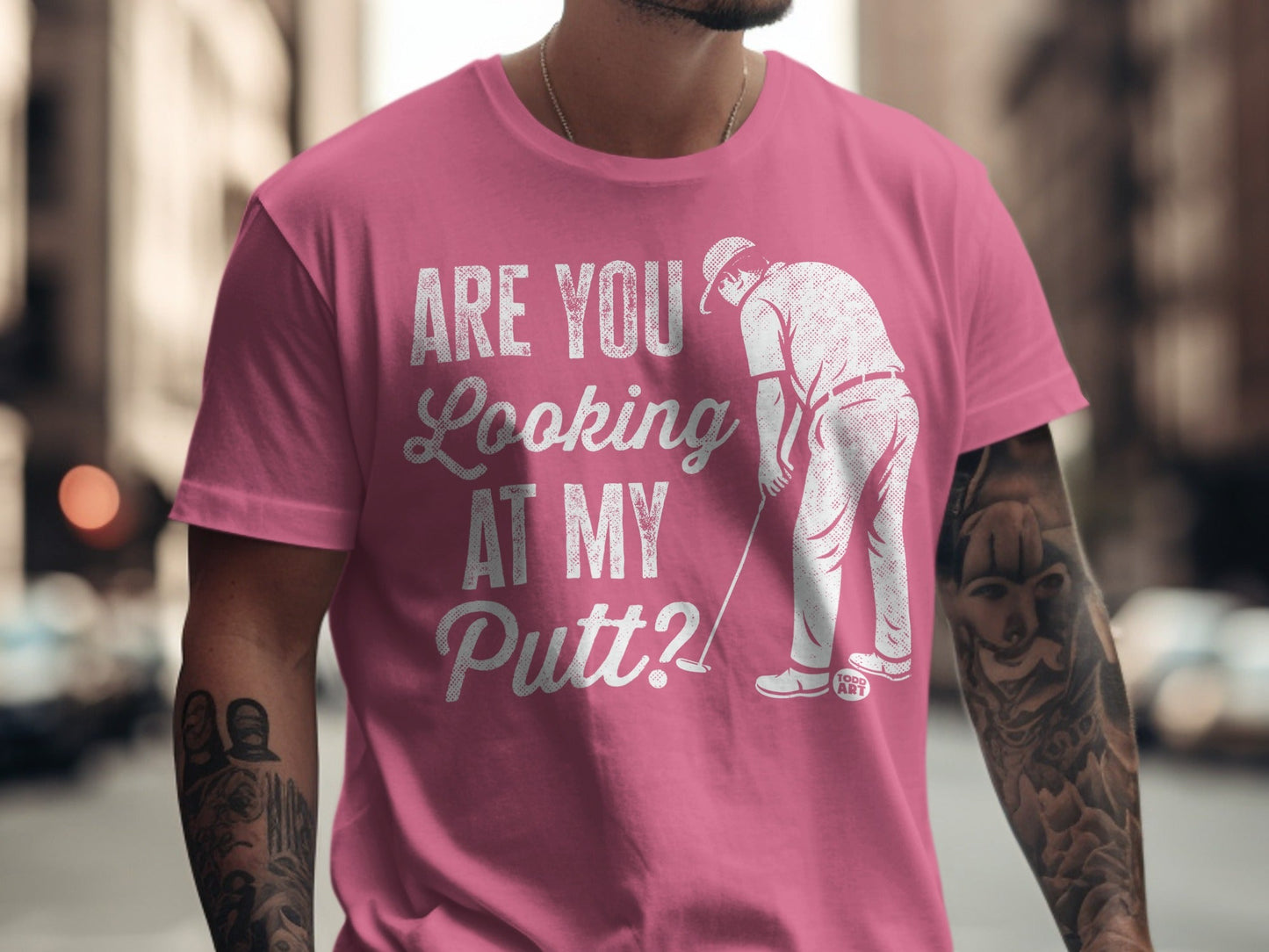 Man wearing pink t-shirt with white text: "Are you looking at my putt?".