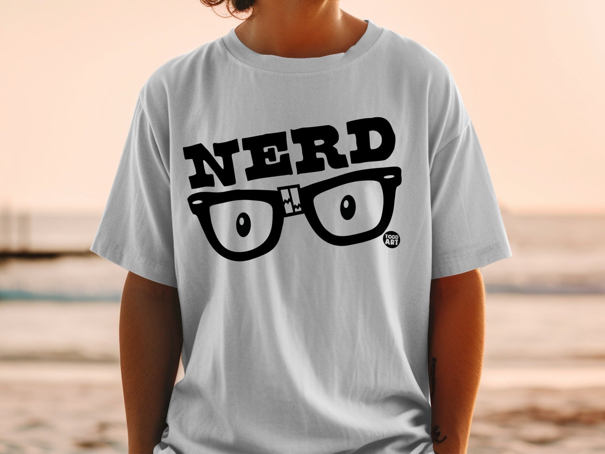 White t-shirt with black "NERD" text and cartoon glasses graphic.